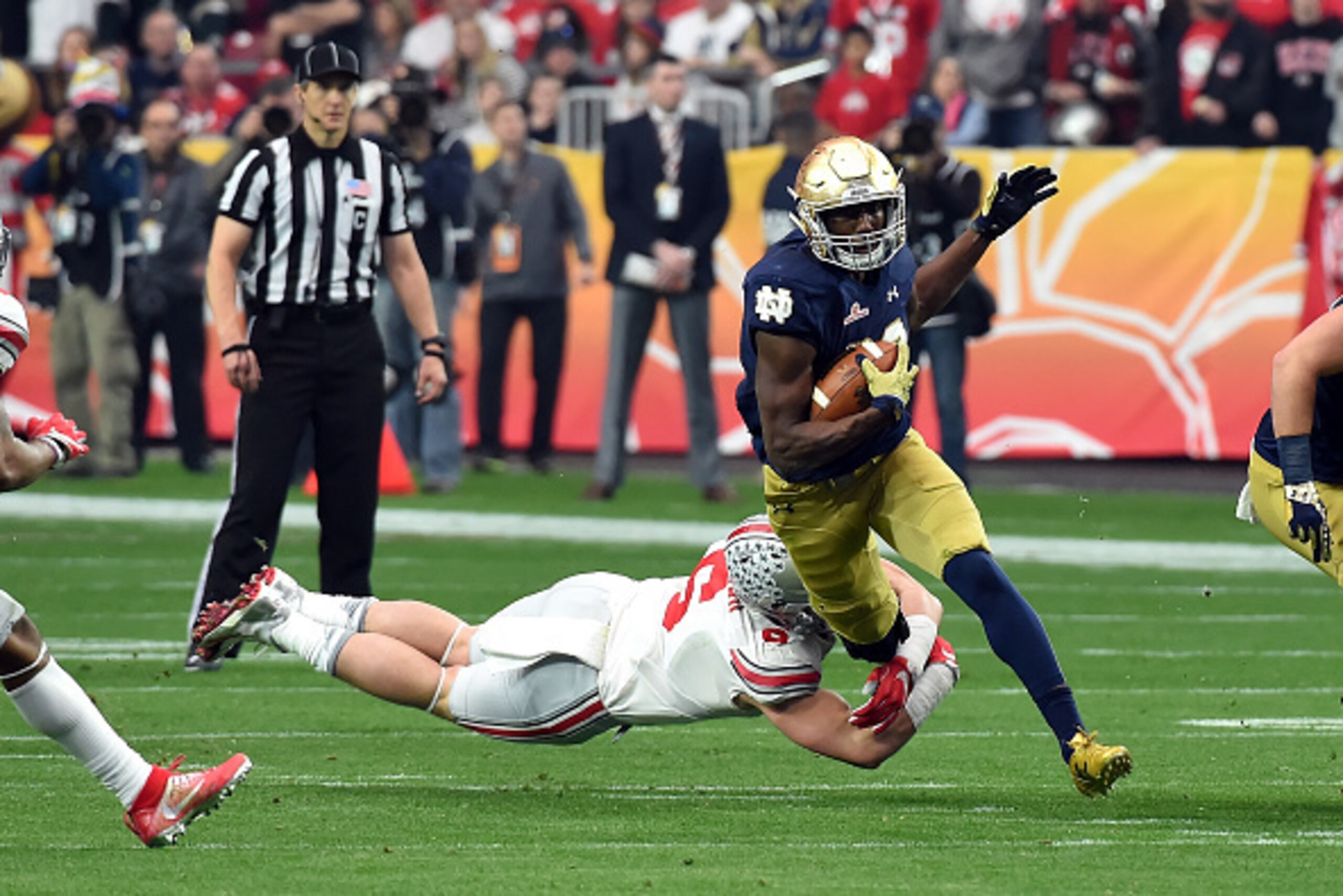 GLENDALE, AZ - JANUARY 01:  Running back Josh Adams #33 of the Notre Dame Fighting Irish breaks a tackle by Sam Hubbard #6 of the Ohio State Buckeyes during the BattleFrog Fiesta Bowl at the University of Phoenix Stadium on January 1, 2016 in Glendale, Ar