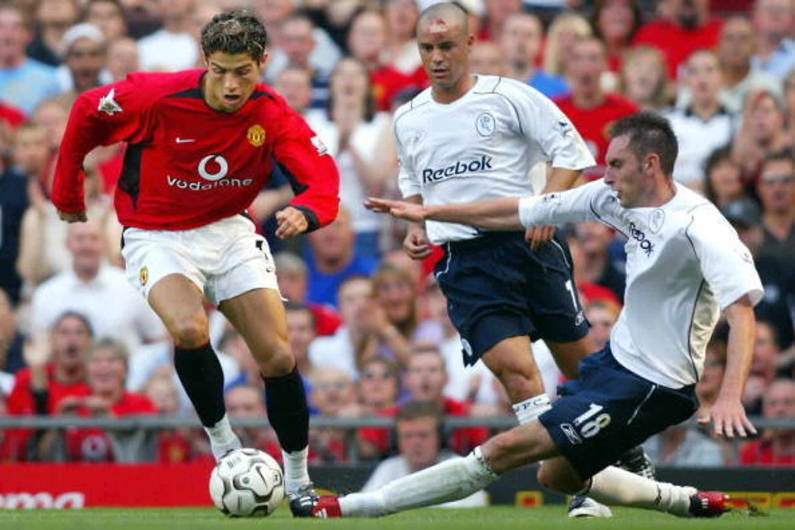 Manchester United's Cristiano Ronaldo (L) takes the ball past Stylianos Giannakopoulos (back) and Nicky Hunt (R) of Bolton Wanderers during the first Premiership match of the season at Old Trafford in Manchester, 16 August 2003. Ronaldo, making his debut,