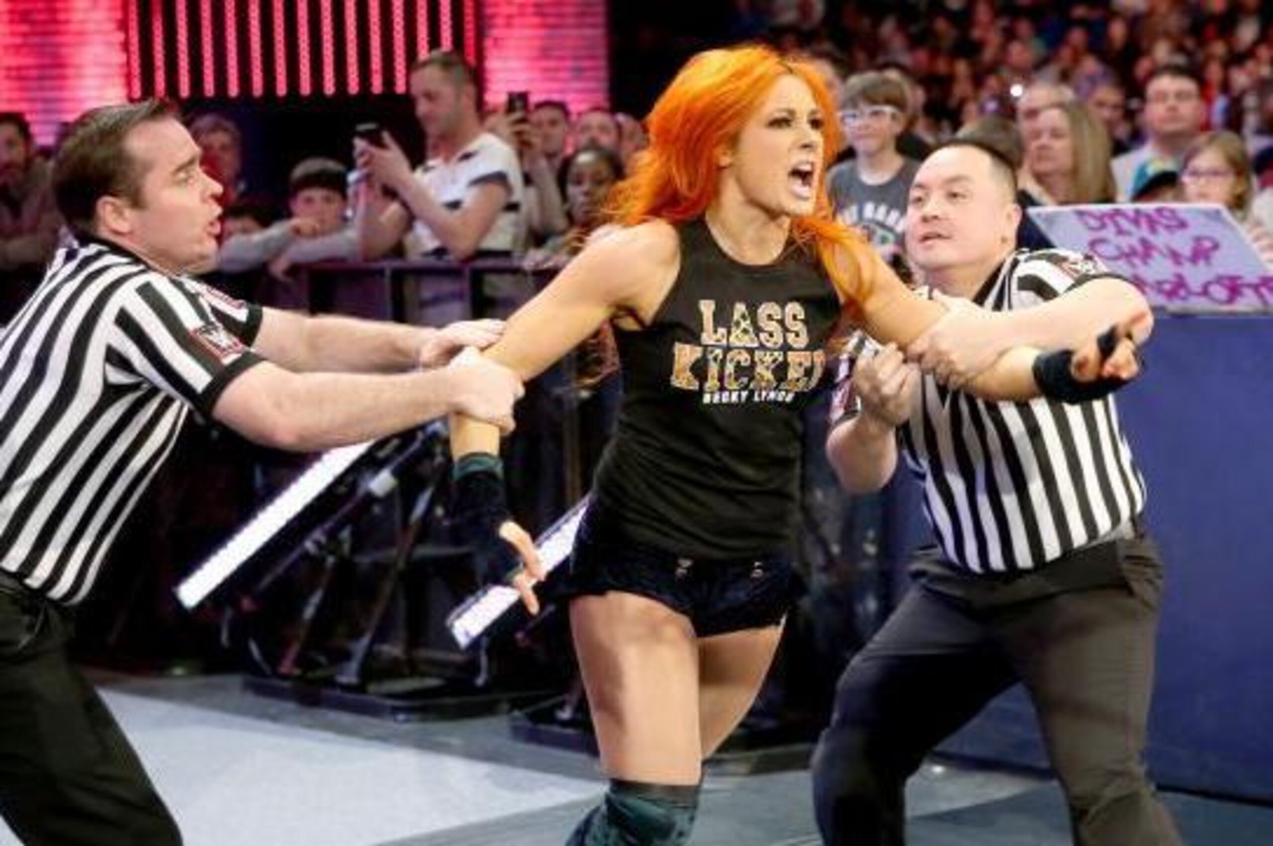 Officials have to restrain Becky Lynch.