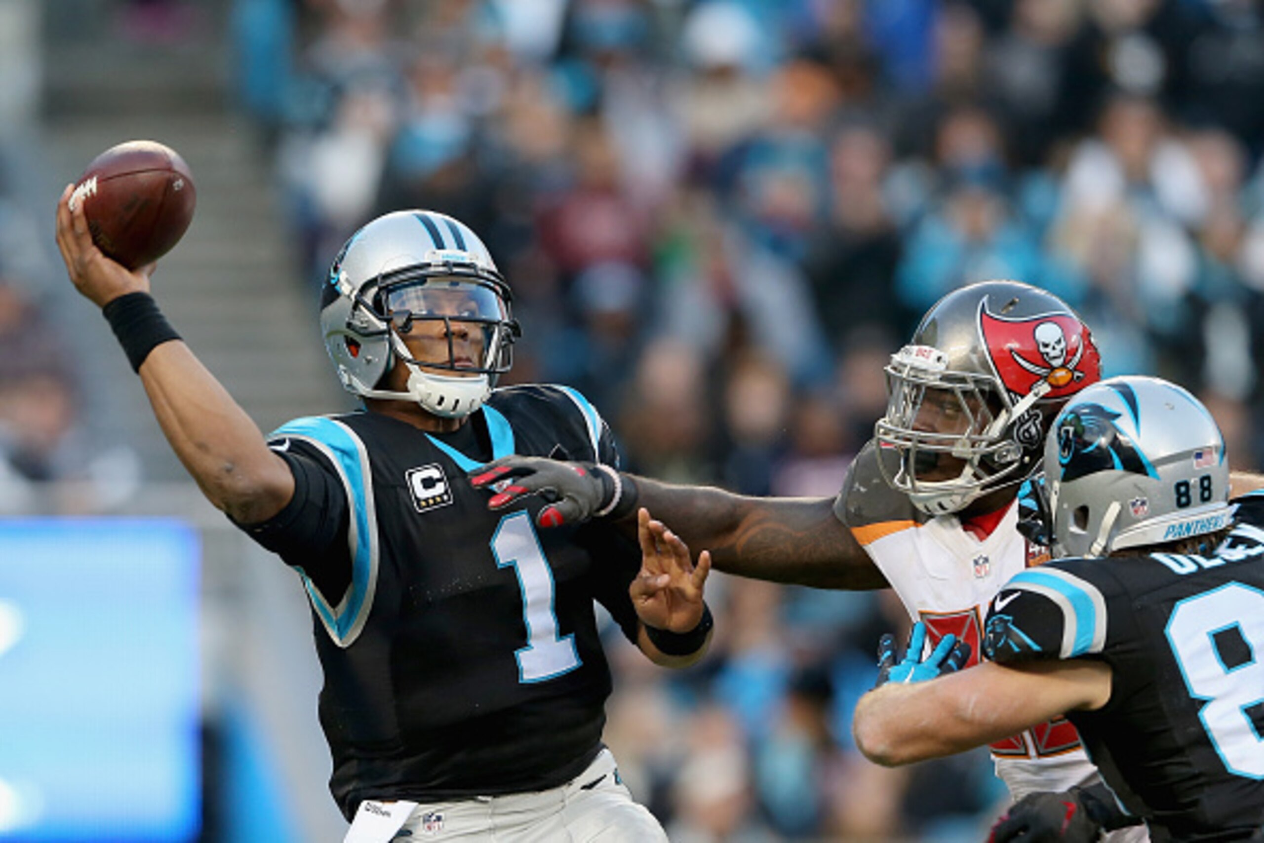 CHARLOTTE, NC - JANUARY 03:   Greg Olsen #88 tries to protect teammate  Cam Newton #1 of the Carolina Panthers from the Tampa Bay Buccaneers pass rush in the 1st quarter during their game at Bank of America Stadium on January 3, 2016 in Charlotte, North C