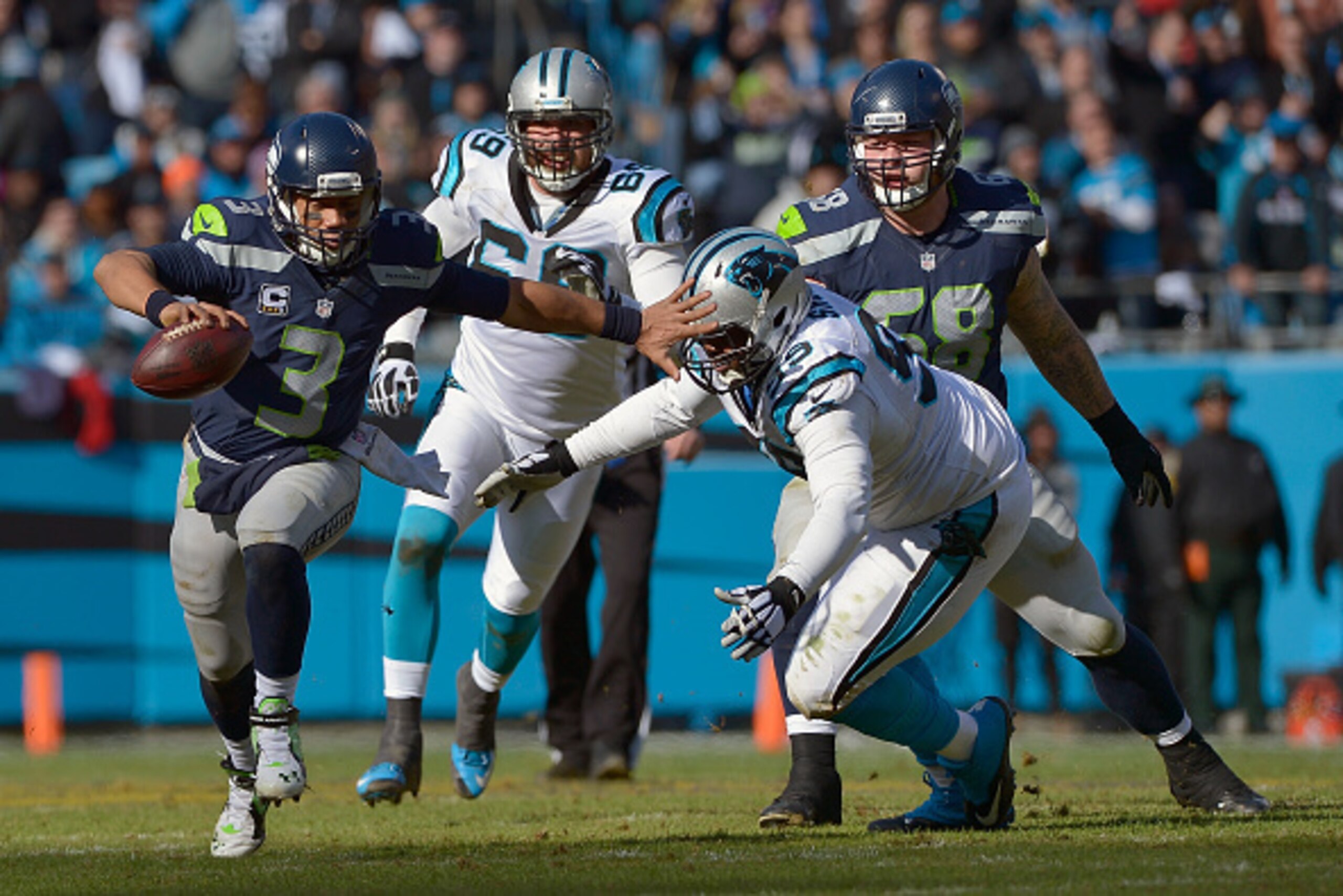 CHARLOTTE, NC - JANUARY 17:  Russell Wilson #3 of the Seattle Seahawks scrambles from  Kawann Short #99 of the Carolina Panthers in the 2nd quarter during the NFC Divisional Playoff Game at Bank of America Stadium on January 17, 2016 in Charlotte, North C