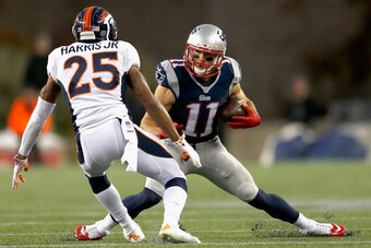FOXBORO, MA - NOVEMBER 02:  Julian Edelman #11 of the New England Patriots evades a tackle by Chris Harris Jr. #25 of the Denver Broncos during the first quarter at Gillette Stadium on November 2, 2014 in Foxboro, Massachusetts.  (Photo by Jim Rogash/Gett
