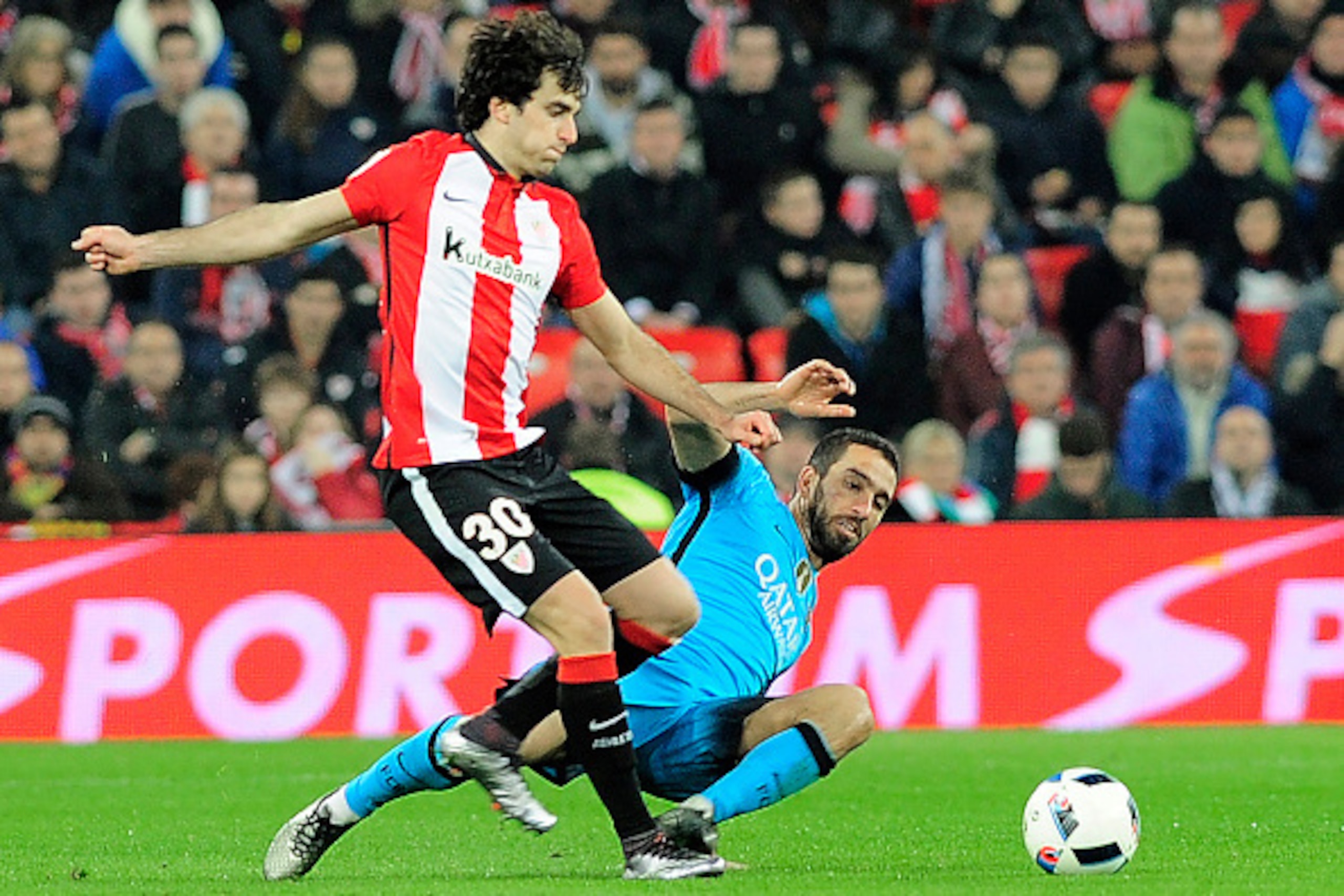 Athletic Bilbao's defende Inigo Lekue (L) vies with Barcelona's Turkish midfielder Arda Turan during the Spanish Copa del Rey (King's Cup) football match Athletic Club de Bilbao vs FC Barcelona at the San Mames stadium in Bilbao on January 20, 2016. AFP P