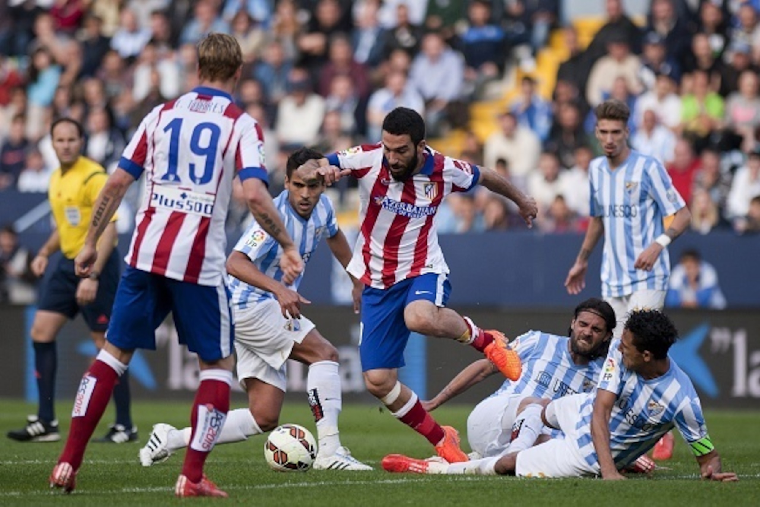Atletico Madrid's Turkish midfielder Arda Turan (L) vies with Malaga's midfielder Jose Luis Garcia Recio (2ndL), defender Sergio Sanchez (2ndR) and Brazilian defender Weligton during the Spanish league football match Malaga CF vs Club Atletico de Madrid a