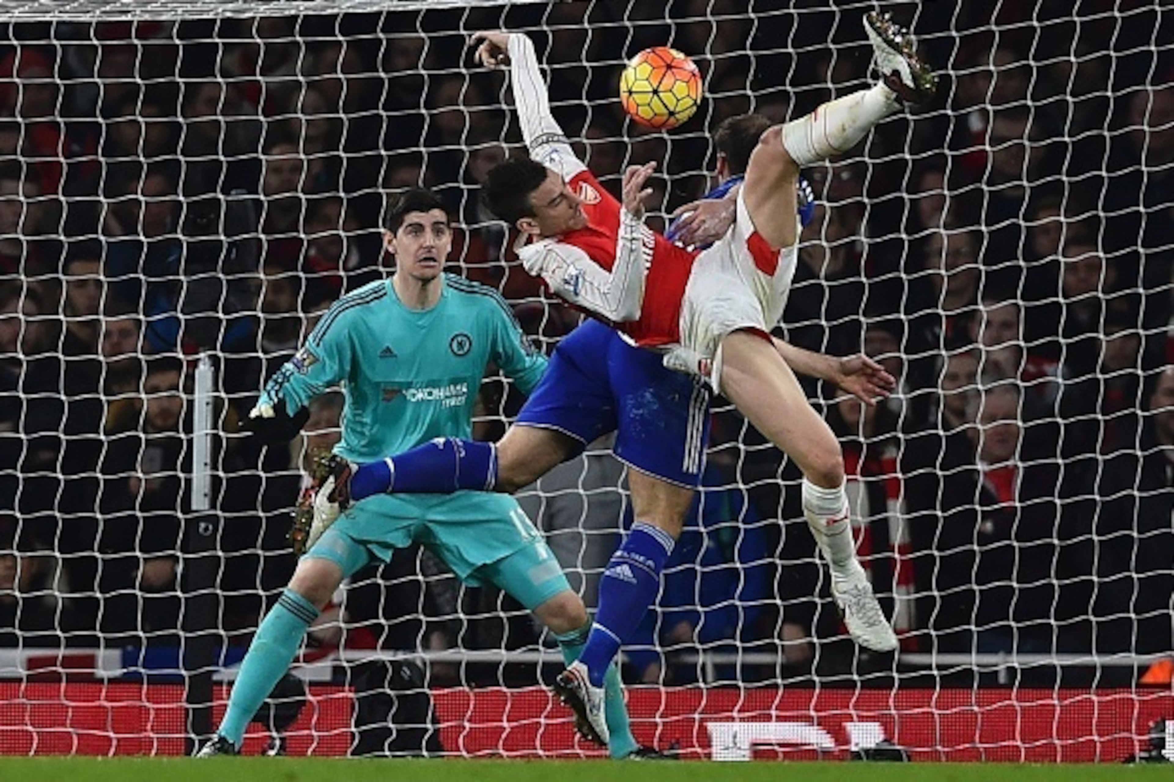 Arsenal's French defender Laurent Koscielny vies with Chelsea's Serbian defender Branislav Ivanovic as Chelsea's Belgian goalkeeper Thibaut Courtois (L) looks on during the English Premier League football match between Arsenal and Chelsea at the Emirates 