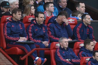 Manchester United's Dutch manager Louis van Gaal (top row 2R) raise a hand to his forehead as he sits next to Manchester United's Welsh assistant manager Ryan Giggs (top row R) in the dug out during the English Premier League football match between Manche