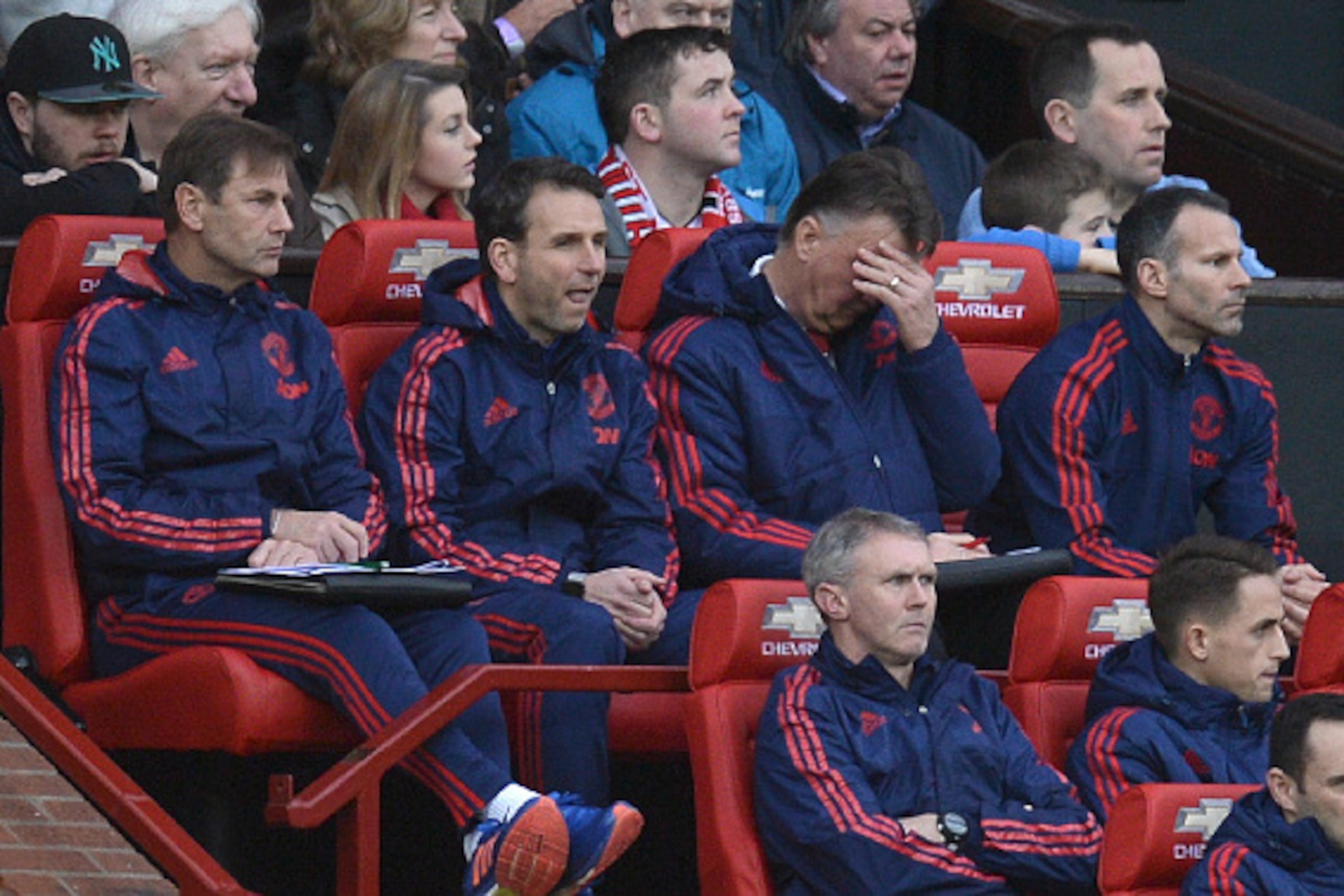 Manchester United's Dutch manager Louis van Gaal (top row 2R) raise a hand to his forehead as he sits next to Manchester United's Welsh assistant manager Ryan Giggs (top row R) in the dug out during the English Premier League football match between Manche