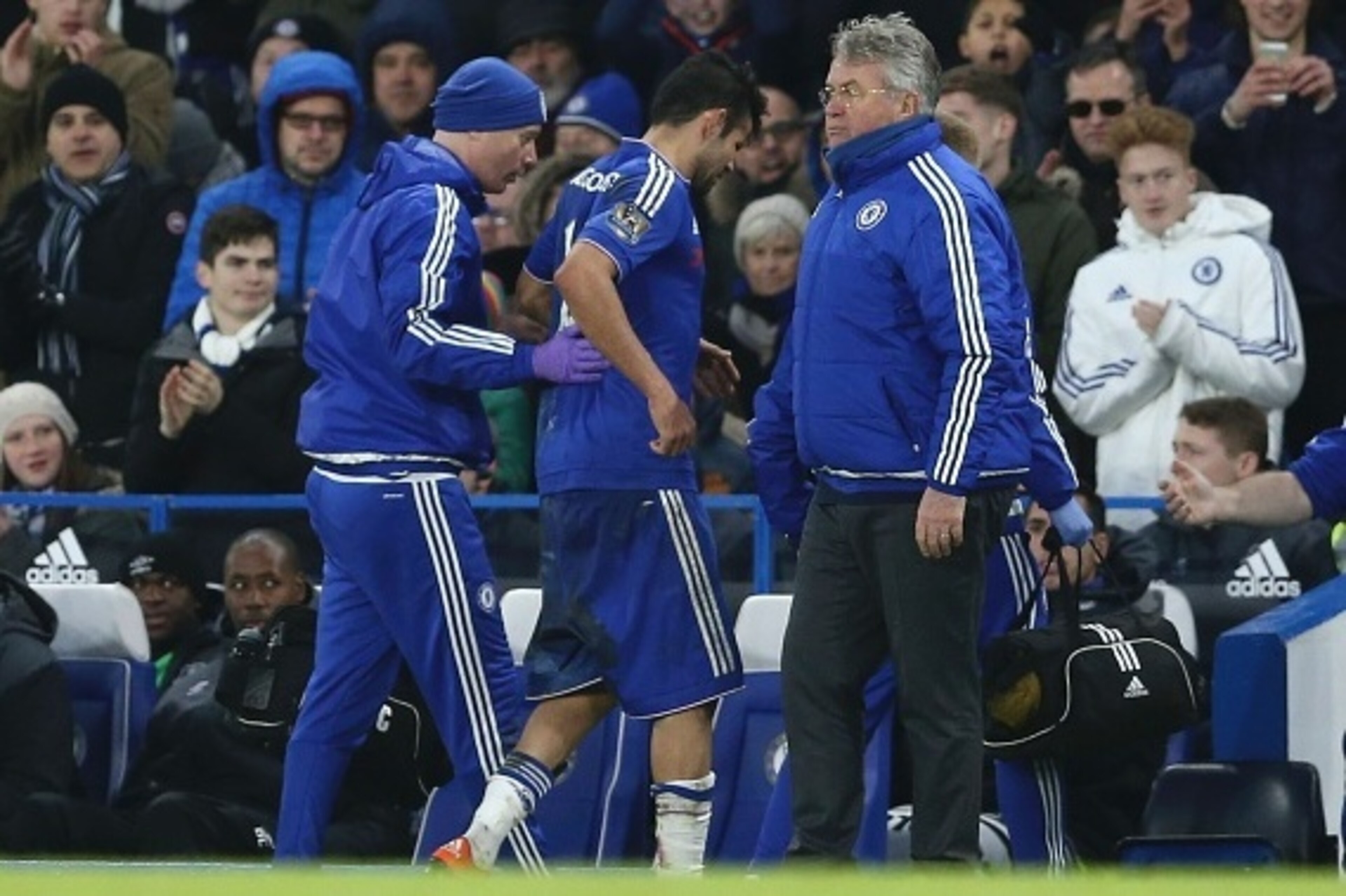 Chelsea's Brazilian-born Spanish striker Diego Costa (C) is helped from the field injured past Chelsea's Dutch manager Guus Hiddink (R) during the English Premier League football match between Chelsea and Everton at Stamford Bridge in London on January 16