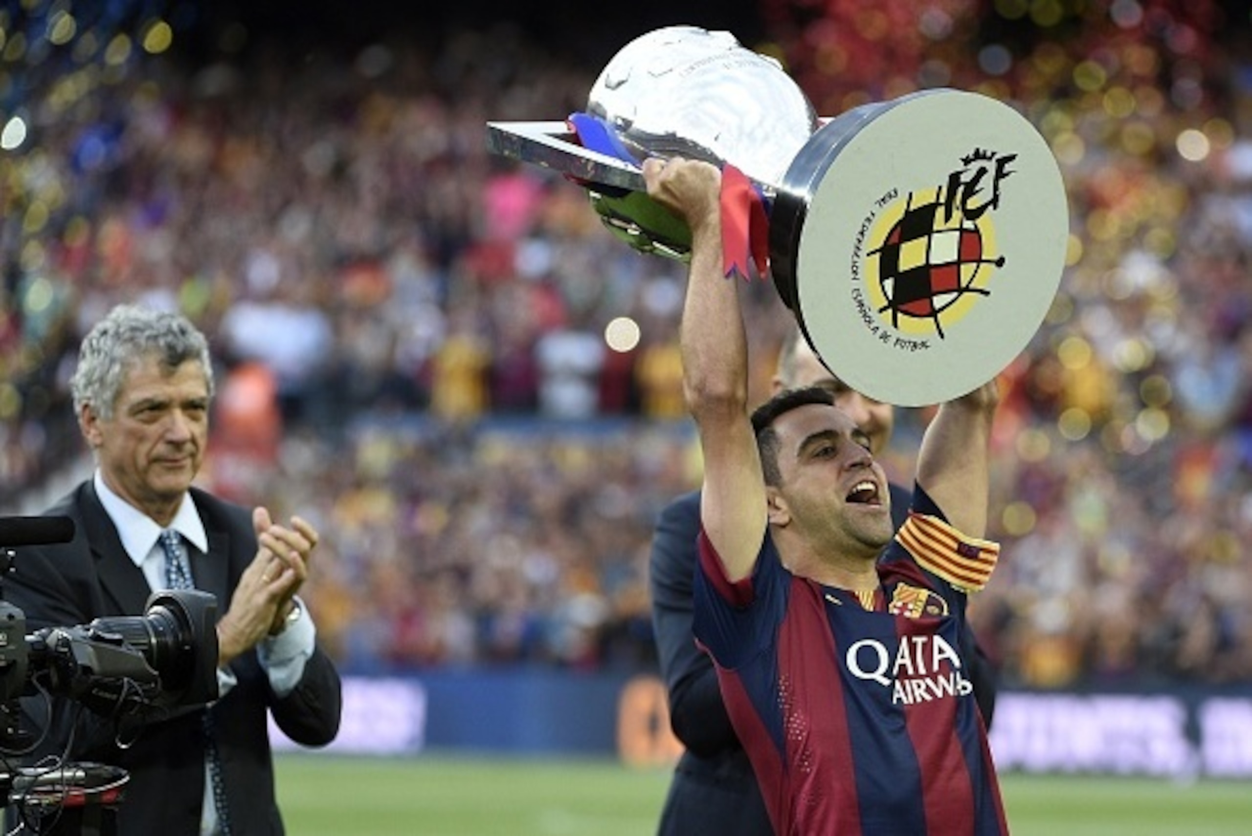 Barcelona's midfielder Xavi Hernandez holds up the trophy for the Spanish league title of 2014/15 as president of Spanish Football Association Angel Maria Villar (L) looks on after the Spanish league football match FC Barcelona vs RC Deportivo La Coruna a