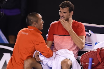 Bulgaria's Grigor Dimitrov (R) is attended by medical staff during his men's singles match against Switzerland's Roger Federer on day five of the 2016 Australian Open tennis tournament in Melbourne on January 22, 2016. AFP PHOTO / GREG WOOD-- IMAGE RESTRI