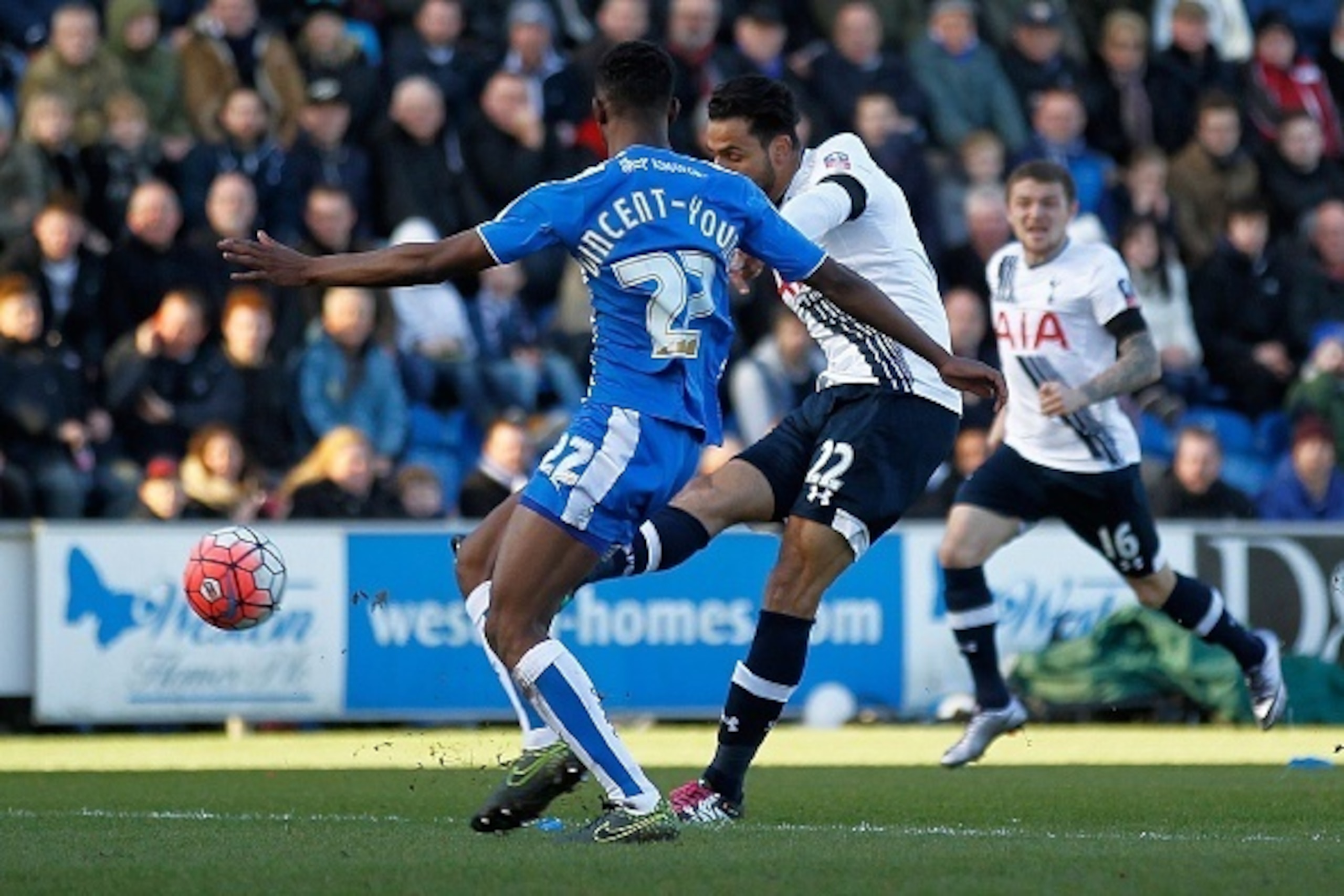Tottenham Hotspur's Belgian midfielder Nacer Chadli (C) shoots past Colchester United's English defender Kane Vincent-Young during the English FA Cup fourth round football match between Colchester United and Tottenham Hotspur at the Weston Homes Community