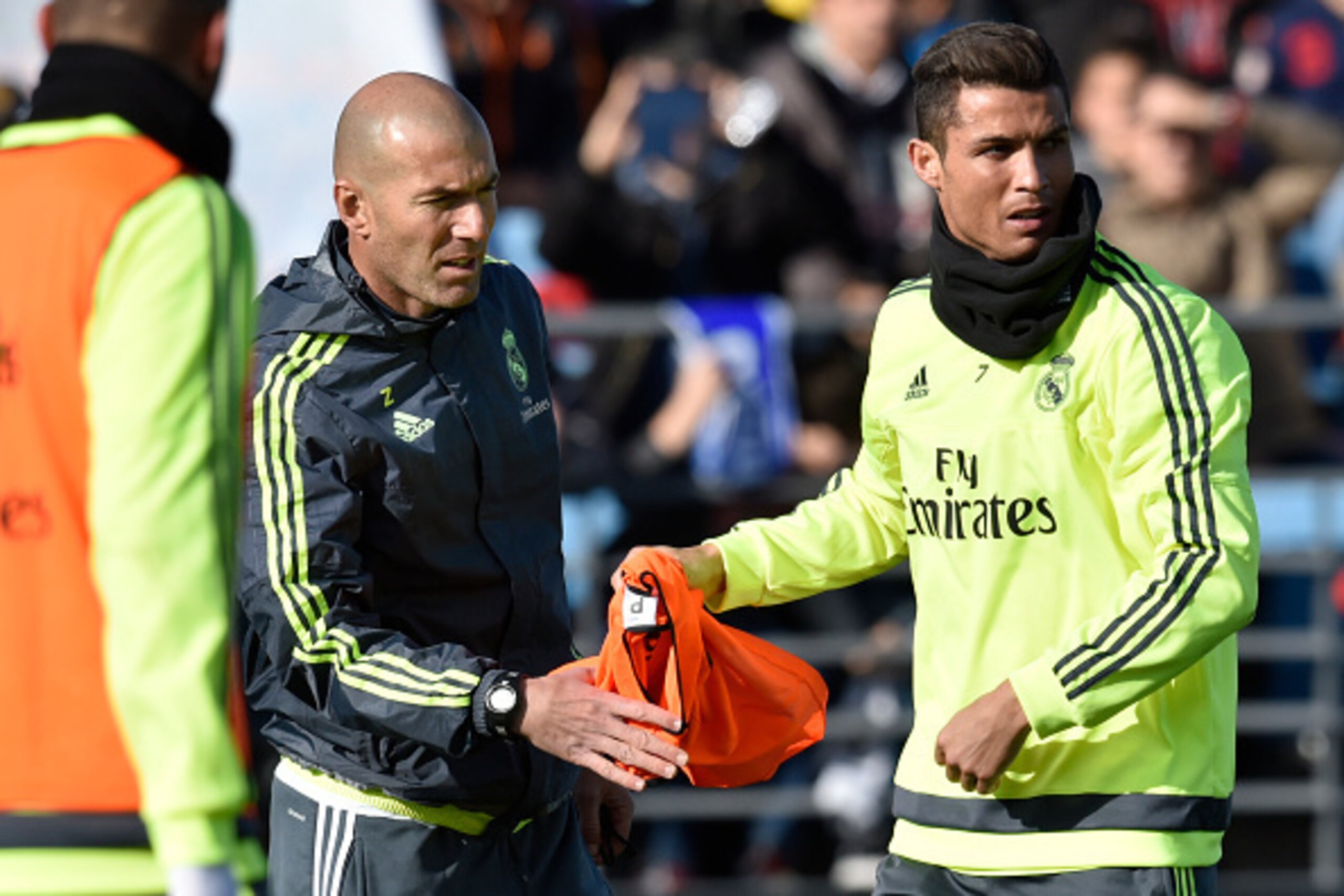 Real Madrid's Portuguese forward Cristiano Ronaldo (R) gives a bib to Real Madrid's new French coach Zinedine Zidane during his first training session as coach of Real Madrid at the Alfredo di Stefano stadium in Valdebebas, on the outskirts of Madrid, on 