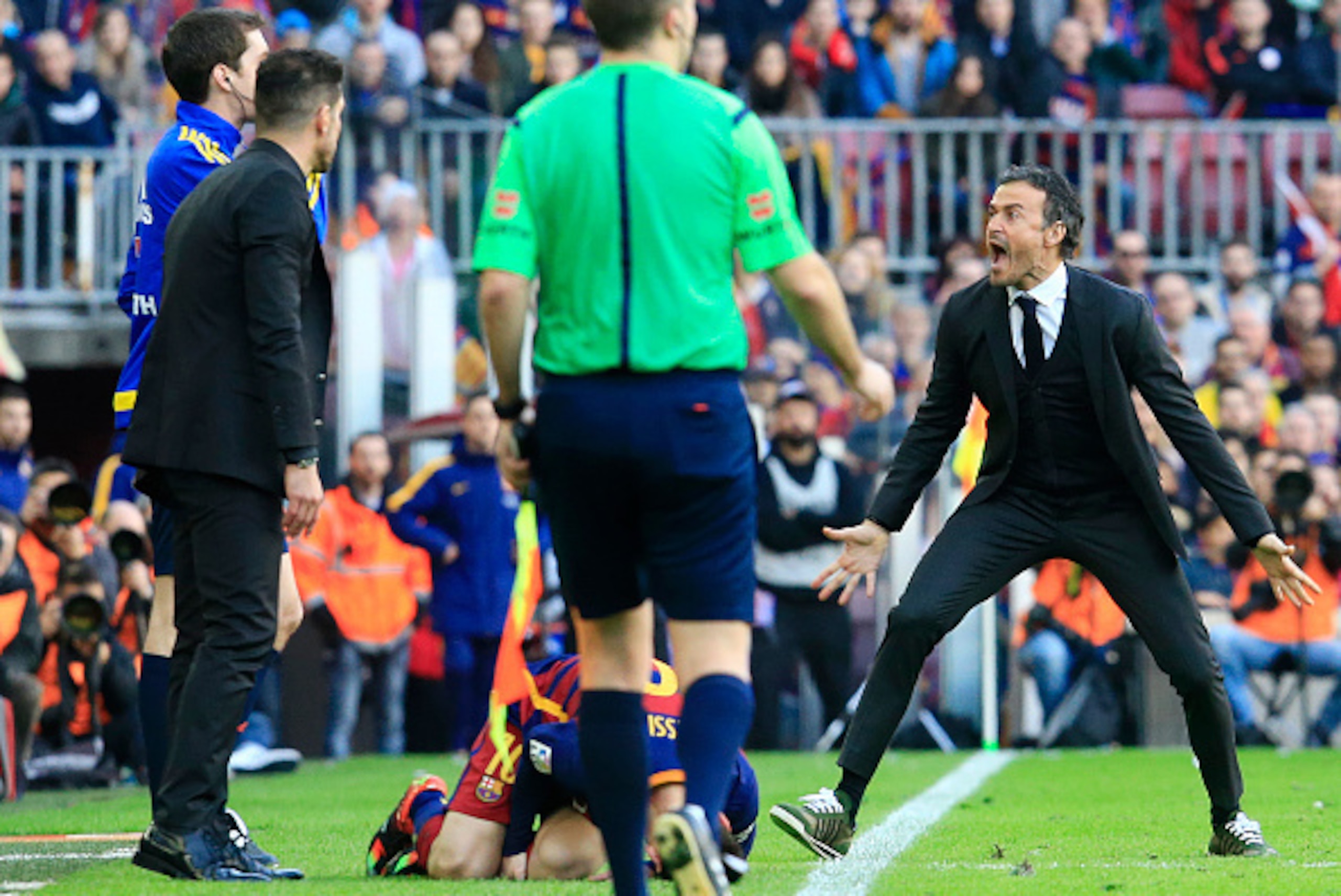 Barcelona's coach Luis Enrique (R) shouts after a fault was committed on Barcelona's Argentinian forward Lionel Messi (down) during the Spanish league football match FC Barcelona vs Club Atletico de Madrid at the Camp Nou stadium in Barcelona on January 3