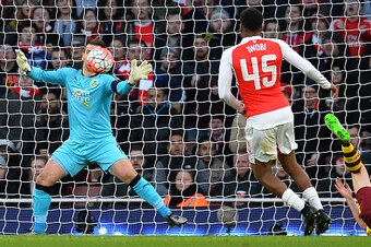 Arsenal's Nigerian striker Alex Iwobi (C) watches as Burnley's English goalkeeper Tom Heaton attempts to stop a shot by Arsenal's Spanish midfielder Santi Cazorla (not pictured) going into his net during the English FA Cup fourth round football match betw