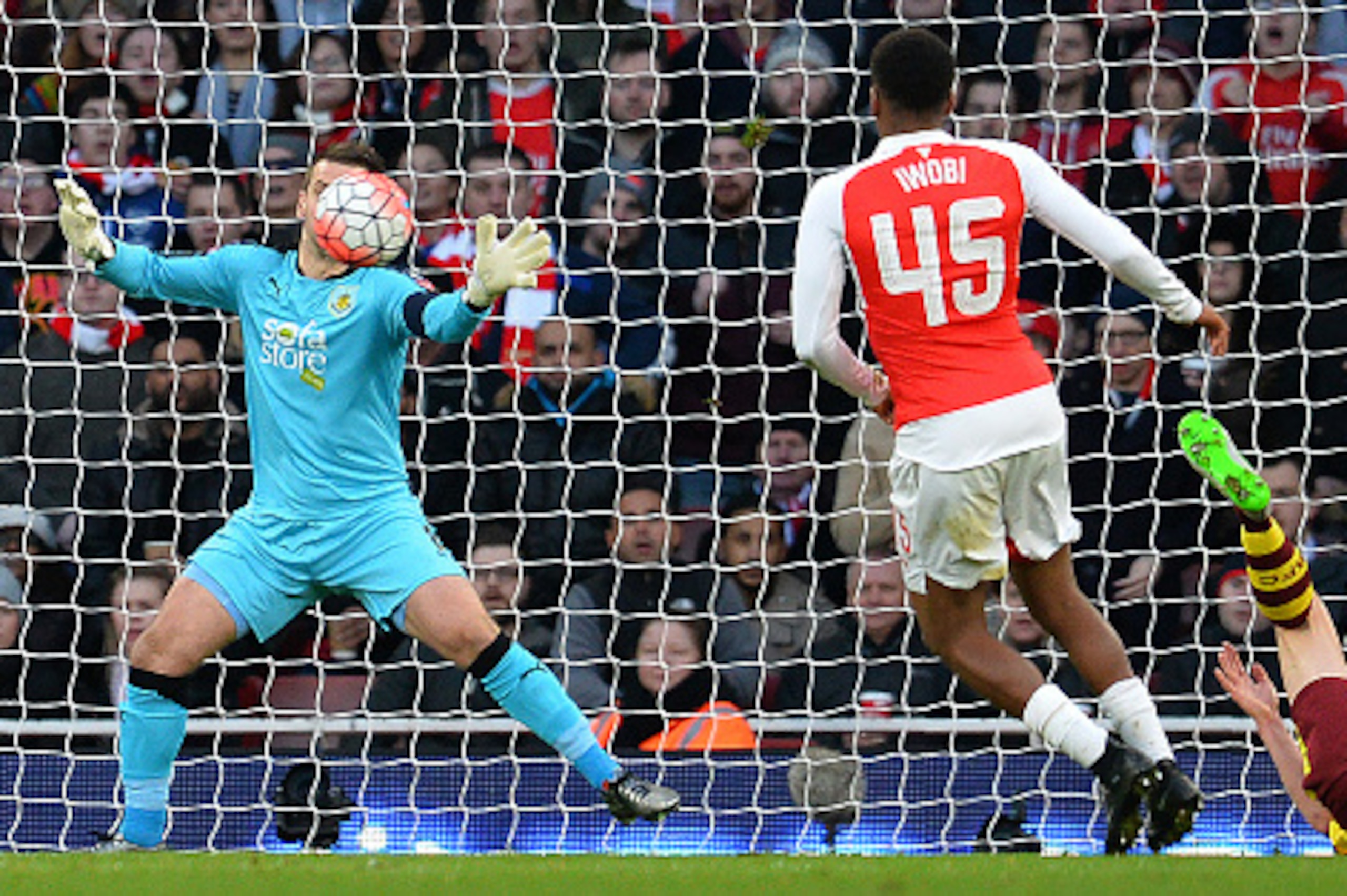 Arsenal's Nigerian striker Alex Iwobi (C) watches as Burnley's English goalkeeper Tom Heaton attempts to stop a shot by Arsenal's Spanish midfielder Santi Cazorla (not pictured) going into his net during the English FA Cup fourth round football match betw