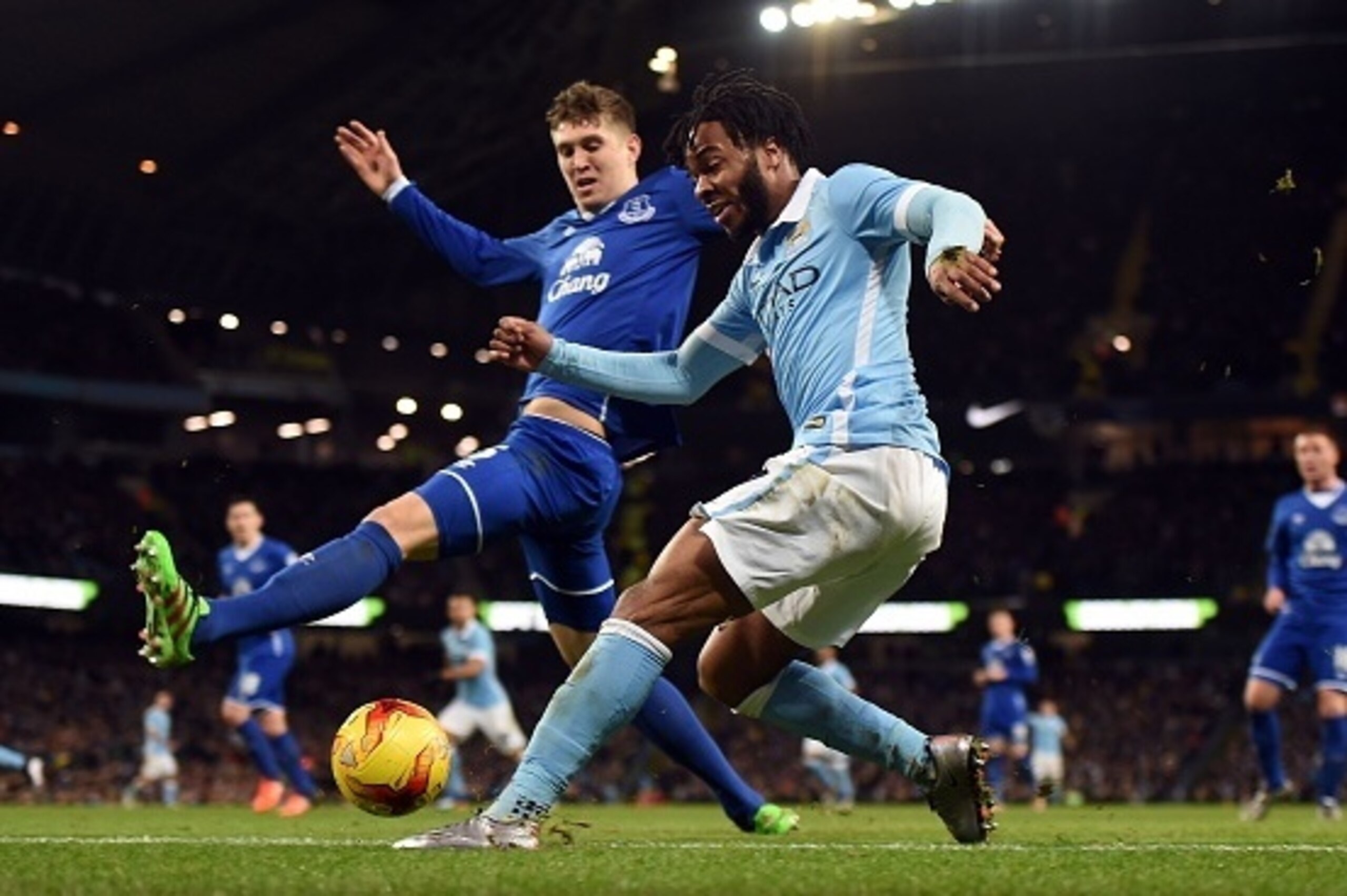 Everton's English defender John Stones (L) tries to block as Manchester City's English midfielder Raheem Sterling crosses the ball as it goes out of play during the English League Cup semi-final second leg football match between Manchester City and Everto