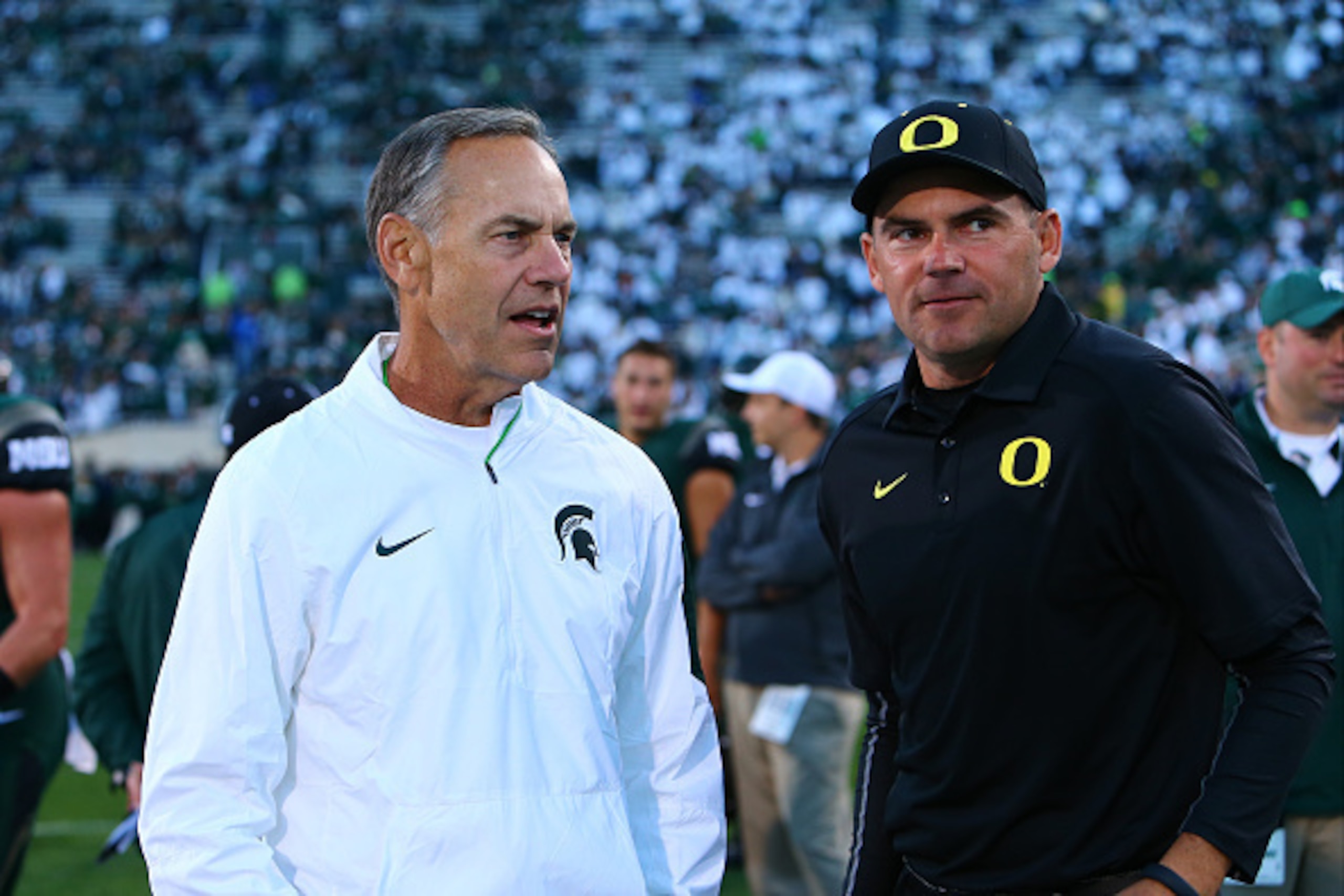 EAST LANSING, MI - SEPTEMBER 12: Head coach Mark Dantonio of the Michigan State Spartans talks to Head coach Mark Helfrich of the Oregon Ducks prior to the start of the game at Spartan Stadium on September 12, 2015 in East Lansing, Michigan. (Photo by Rey