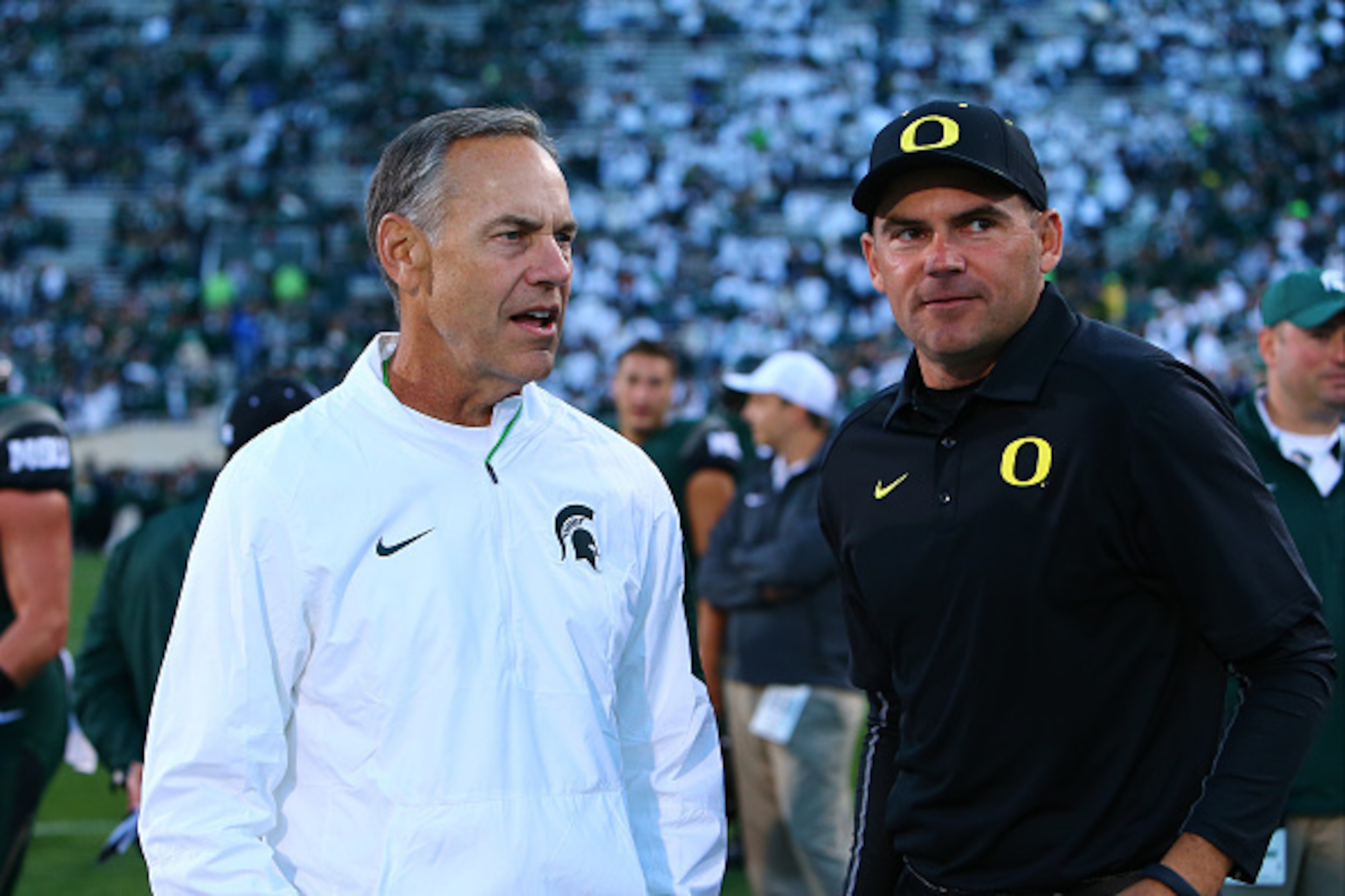 EAST LANSING, MI - SEPTEMBER 12: Head coach Mark Dantonio of the Michigan State Spartans talks to Head coach Mark Helfrich of the Oregon Ducks prior to the start of the game at Spartan Stadium on September 12, 2015 in East Lansing, Michigan. (Photo by Rey