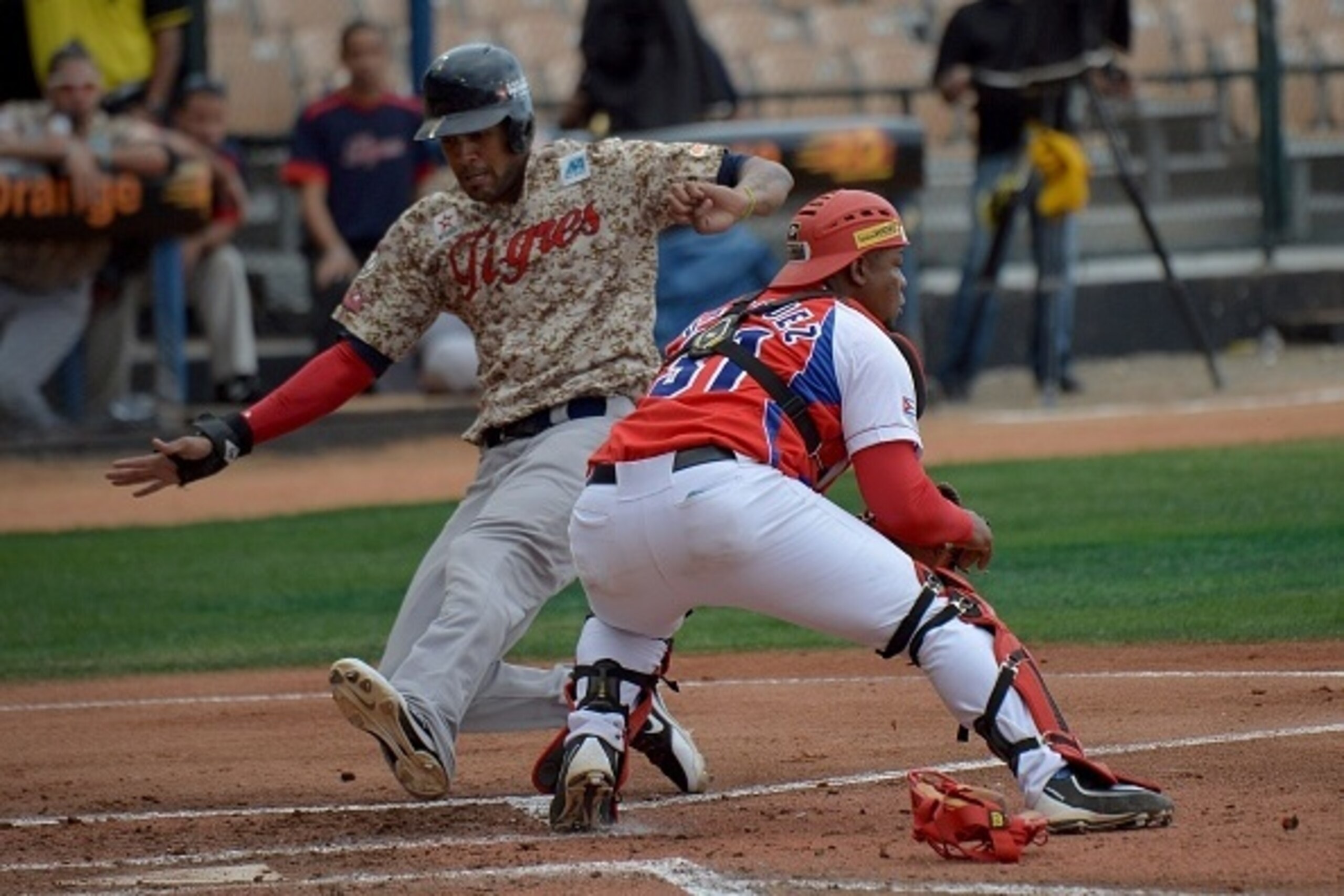 Jose Alberto Martinez (L) of Venezuela slides safe on home base against Cuban during their 2016 Caribbean Baseball Series game in Santo Domingo, Dominican Republic, on February 4, 2016.   AFP PHOTO/YAMIL LAGE / AFP / YAMIL LAGE        (Photo credit should
