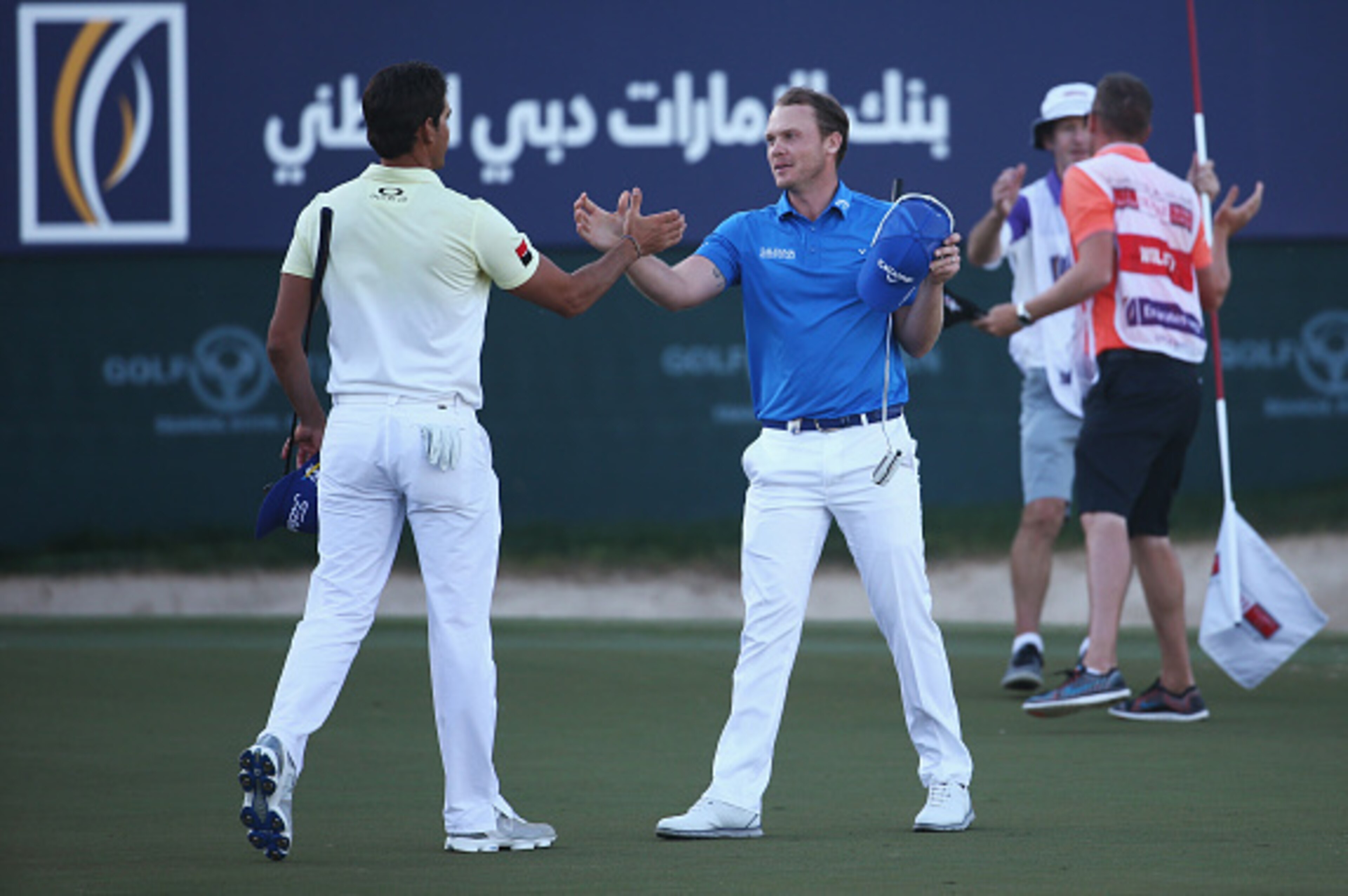 DUBAI, UNITED ARAB EMIRATES - FEBRUARY 07:  Danny Willett of England celebrates his victory on the 18th green as he shakes hands with Rafa Cabrera-Bello of Spain during the final round of the Omega Dubai Desert Classic at the Emirates Golf Club on Februar