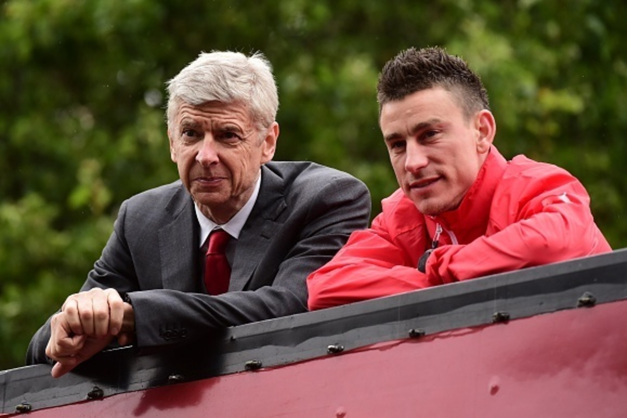 Arsenal's French manager Arsene Wenger (L) and Arsenal's French defender Laurent Koscielny look out from an open top bus during the Arsenal victory parade in London on May 31, 2015, following their win in the English FA Cup final football match on May 30,