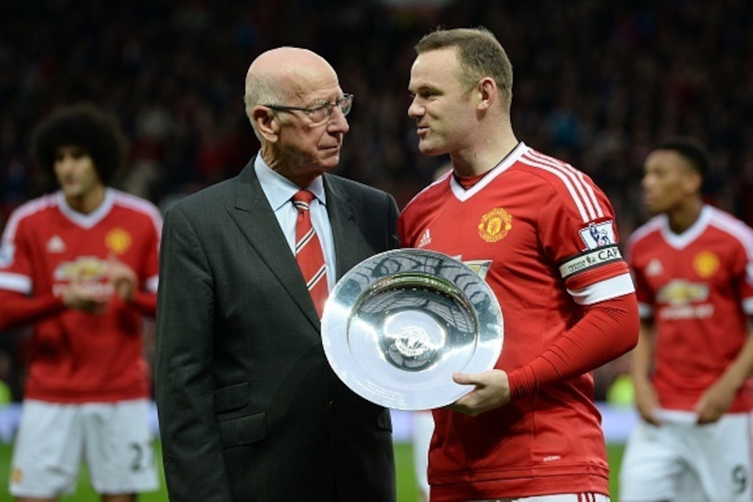 Manchester United's English striker Wayne Rooney receives an award from former Manchester United player Sir Bobby Charlton before playing in his 500th game for his club in the English Premier League football match between Manchester United and Norwich Cit