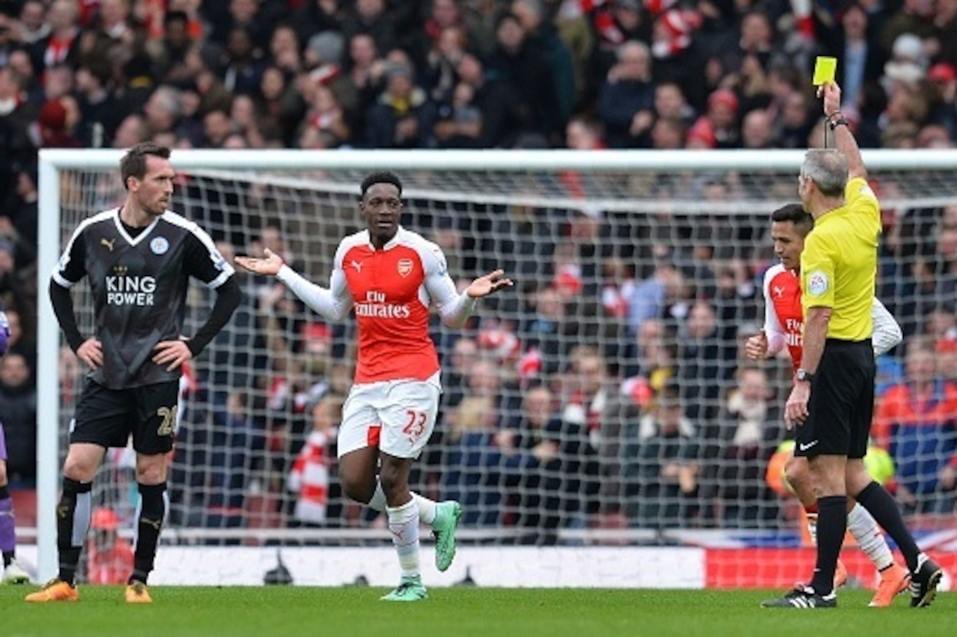 Referee Martin Atkinson shows Arsenal's English striker Danny Welbeck (C) a yellow card during the English Premier League football match between Arsenal and Leicester at the Emirates Stadium in London on February 14, 2016.  / AFP / GLYN KIRK / RESTRICTED 