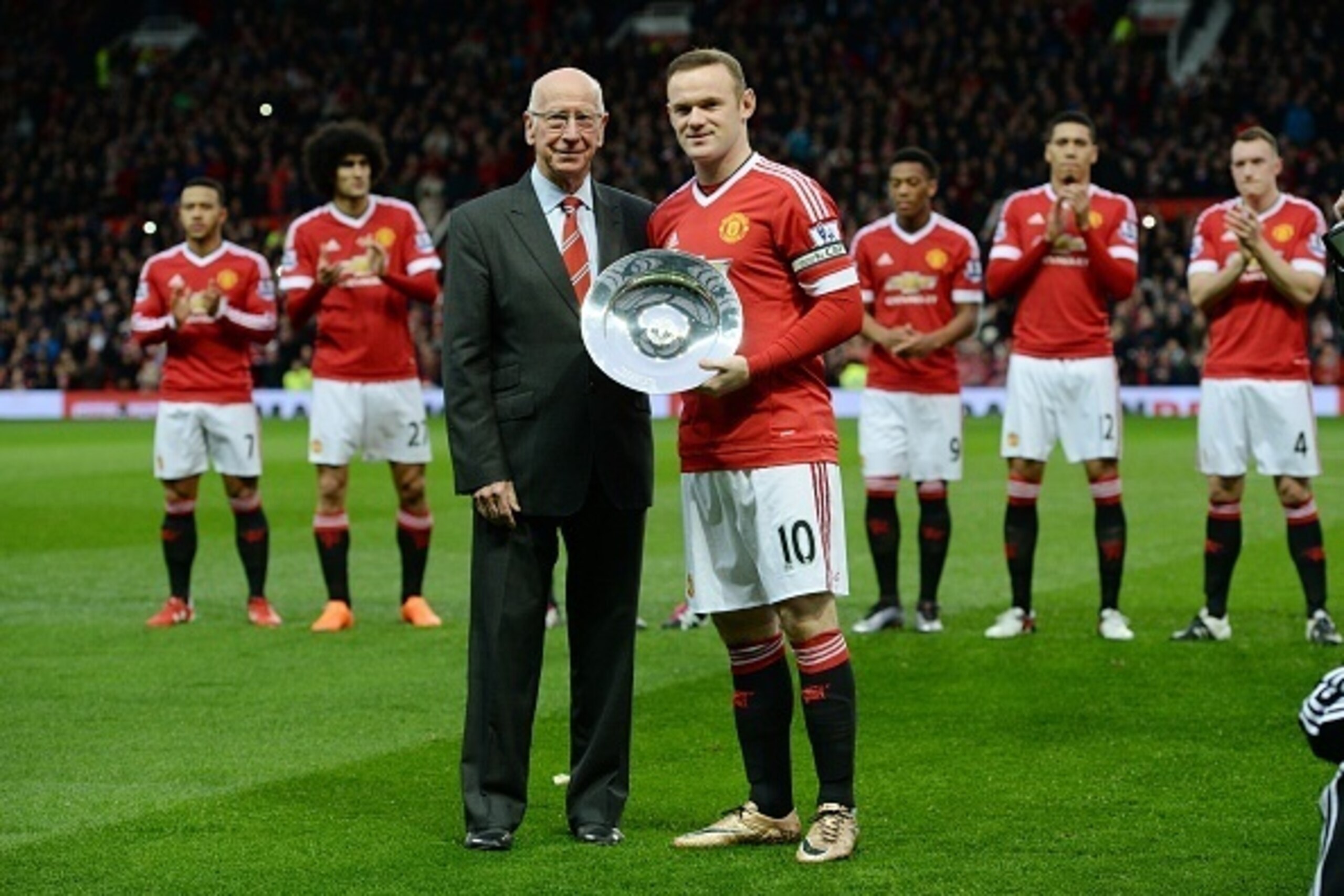 Manchester United's English striker Wayne Rooney receives an award from former Manchester United player Sir Bobby Charlton before playing in his 500th game for his club in the English Premier League football match between Manchester United and Norwich Cit