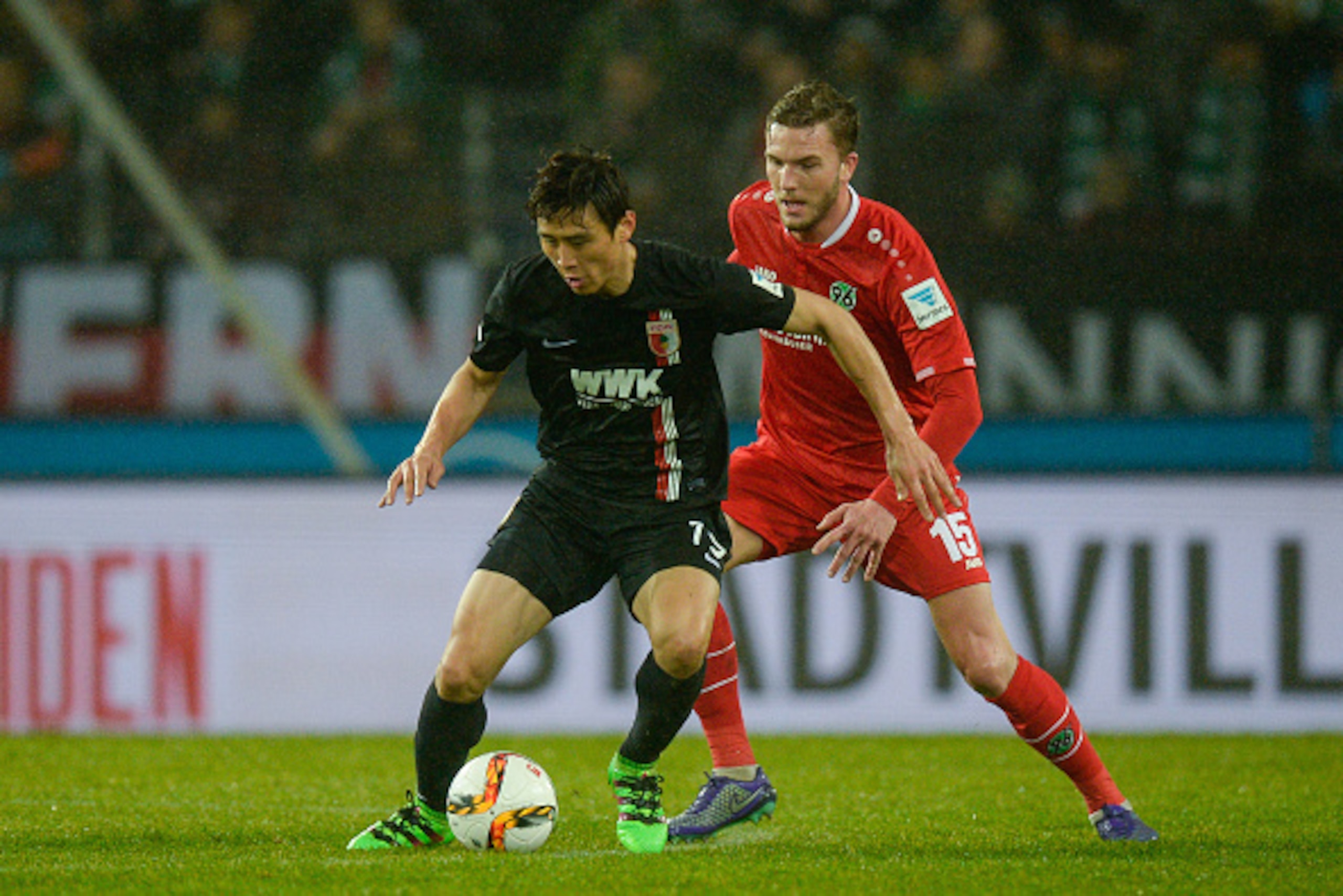 HANOVER, GERMANY - FEBRUARY 21:  Ja-Cheol Koo of Augsburg is challenged by Andre Hoffmann of Hannover during the Bundesliga match between Hannover 96 and FC Augsburg at HDI-Arena on February 21, 2016 in Hanover, Germany.  (Photo by Nigel Treblin/Getty Ima