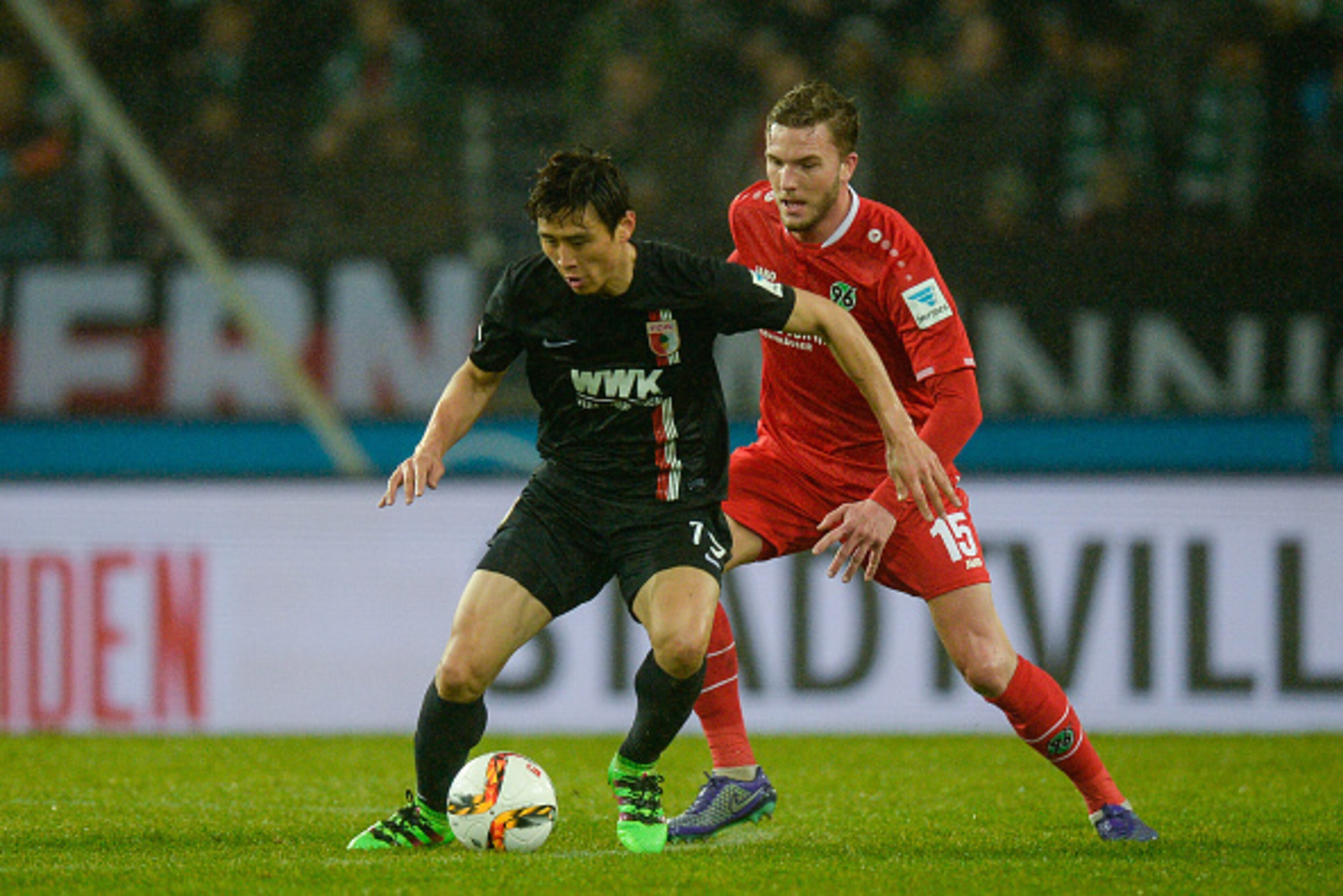 HANOVER, GERMANY - FEBRUARY 21:  Ja-Cheol Koo of Augsburg is challenged by Andre Hoffmann of Hannover during the Bundesliga match between Hannover 96 and FC Augsburg at HDI-Arena on February 21, 2016 in Hanover, Germany.  (Photo by Nigel Treblin/Getty Ima