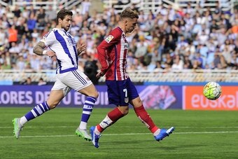Atletico Madrid's French forward Antoine Griezmann (R) shoot to score next to Real Sociedad's defender Inigo Martinez (L) during the Spanish league football match Real Sociedad de Futbol vs Club Atletico de Madrid at the Anoeta stadium in San Sebastian on