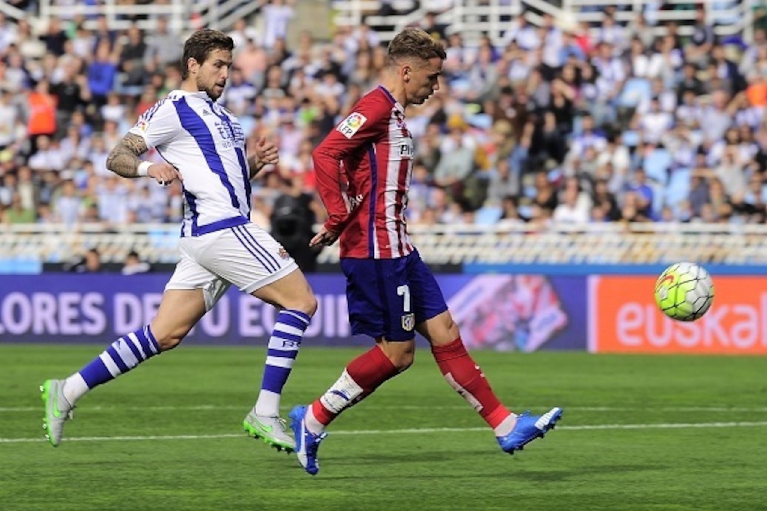 Atletico Madrid's French forward Antoine Griezmann (R) shoot to score next to Real Sociedad's defender Inigo Martinez (L) during the Spanish league football match Real Sociedad de Futbol vs Club Atletico de Madrid at the Anoeta stadium in San Sebastian on