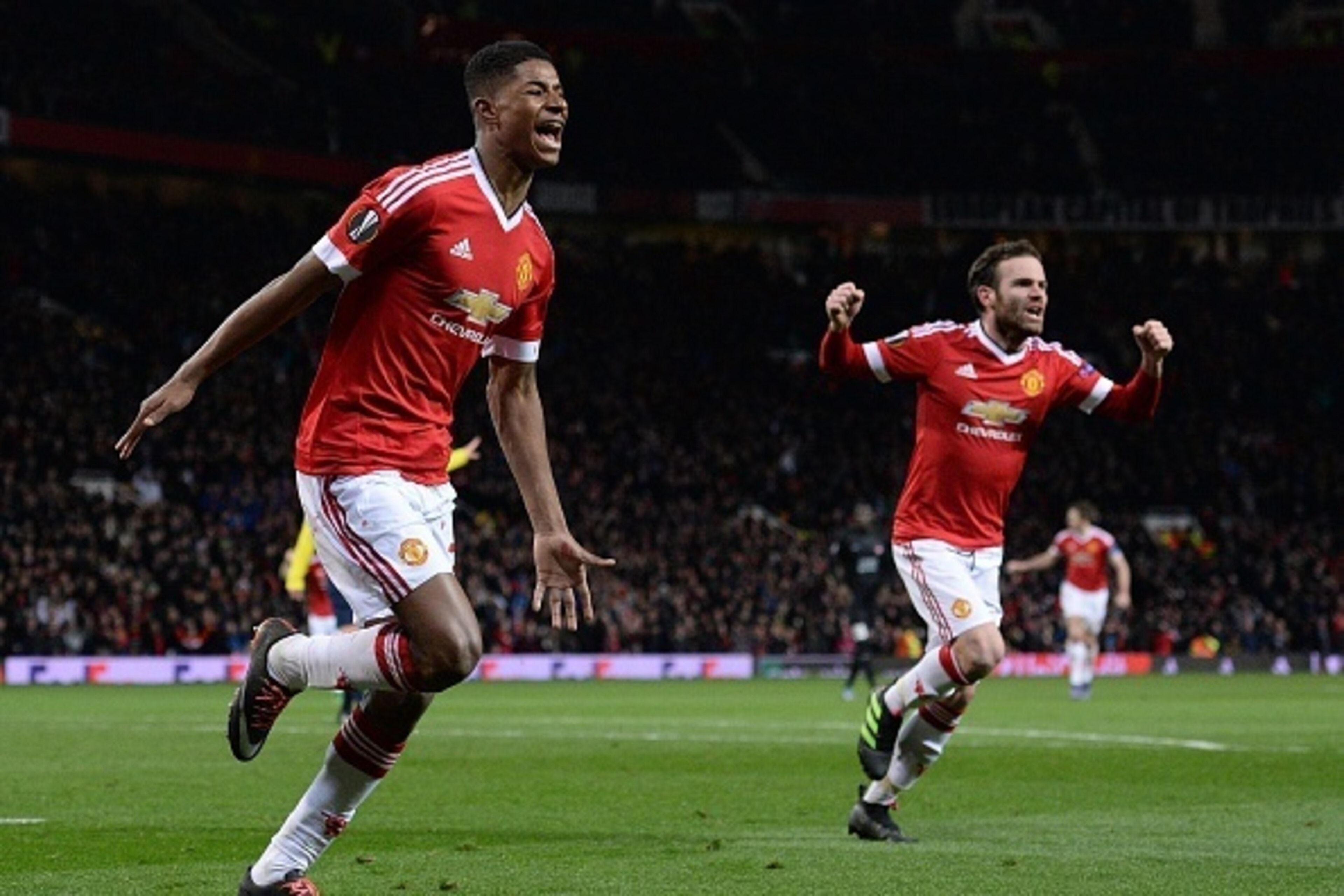 Manchester United's English striker Marcus Rashford (L) celebrates scoring his team's third goal with Manchester United's Spanish midfielder Juan Mata during the UEFA Europa League round of 32, second leg football match between Manchester United and and F