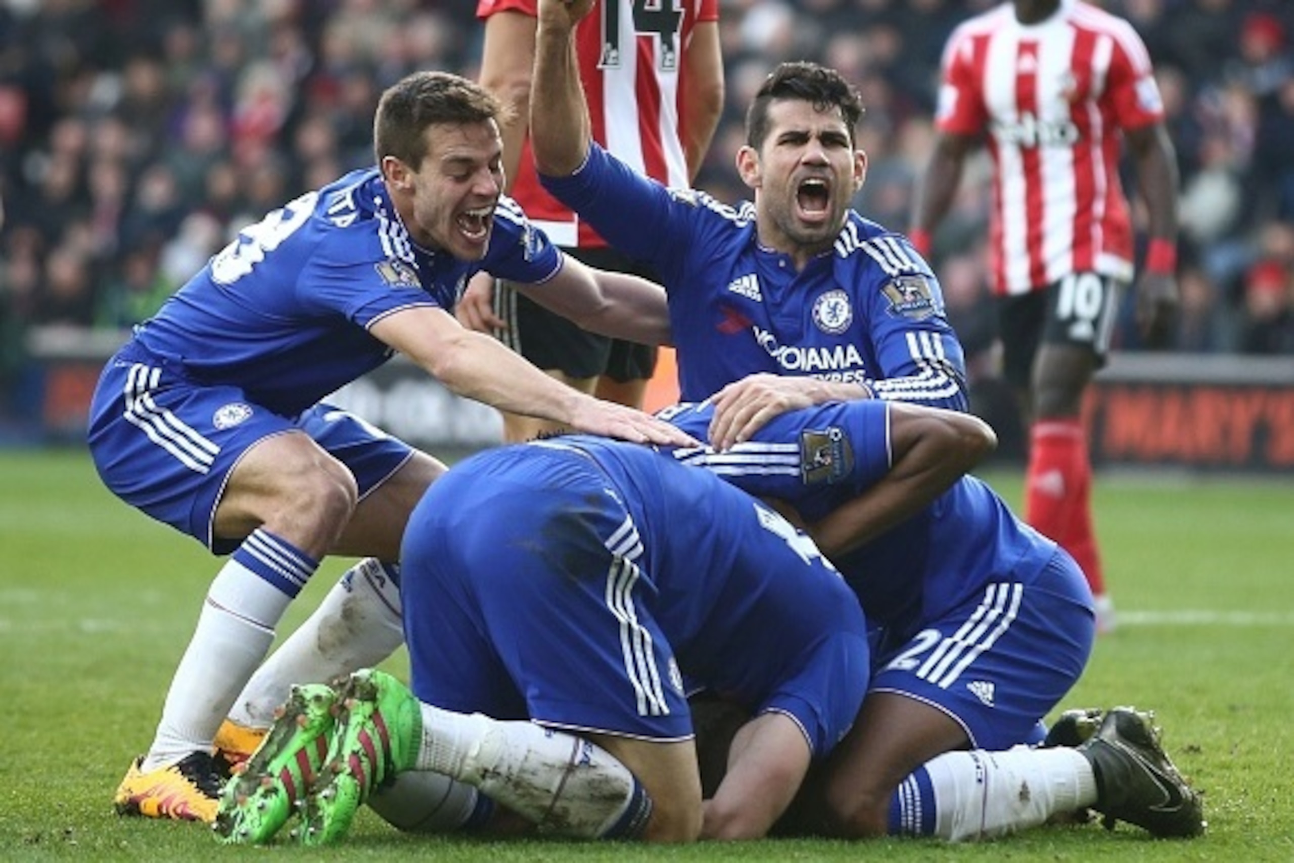Chelsea's Brazilian-born Spanish striker Diego Costa (R top) and Chelsea's Spanish defender Cesar Azpilicueta (top L) join the celebration after Chelsea's Serbian defender Branislav Ivanovic (C floor obscured) scored their second goal during the English P