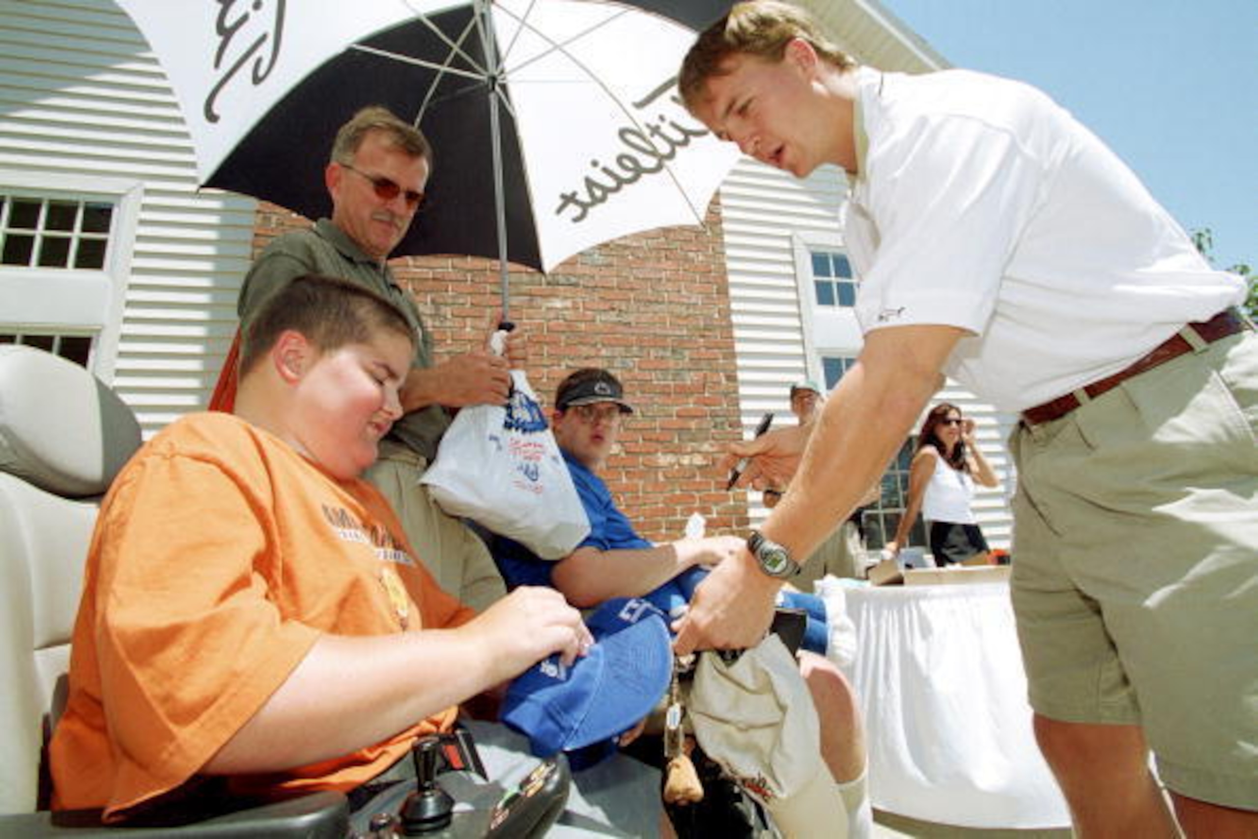 Indianapolis Colts quarterback Peyton Manning (R) presents a hat he has signed to a young man afflicted with muscular dystrophy during the 7/2001 Ken Dilger golf outing benefitting the Muscular Dystrophy Association held at Prairie View Golf Club in Carme