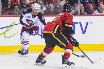 CALGARY, AB - MARCH 21: Kris Russell #4 of the Calgary Flames looks to check Nick Foligno #71 of the Columbus Blue Jackets during an NHL game at Scotiabank Saddledome on March 21, 2015 in Calgary, Alberta, Canada. The Blue Jackets defeated the Flames 3-2 