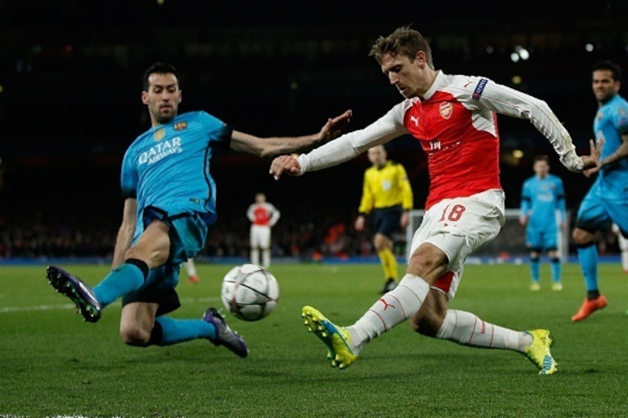 Arsenal's Spanish defender Nacho Monreal(R) crosses the ball past Barcelona's midfielder Sergio Busquets during the UEFA Champions League round of 16 1st leg football match between Arsenal and Barcelona at the Emirates Stadium in London on February 23, 20
