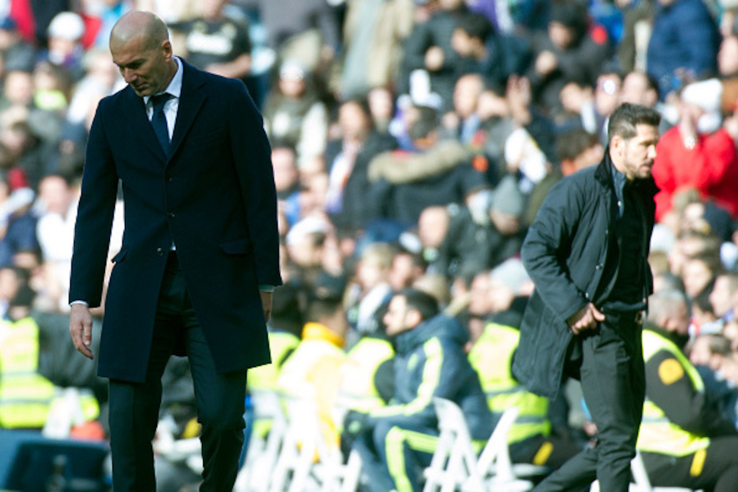 Real Madrid's French coach Zinedine Zidane (L) looks down next to Atletico Madrid's Argentinian coach Diego Simeone during the Spanish league football match Real Madrid CF vs Club Atletico de Madrid at the Santiago Bernabeu stadium in Madrid on February 2
