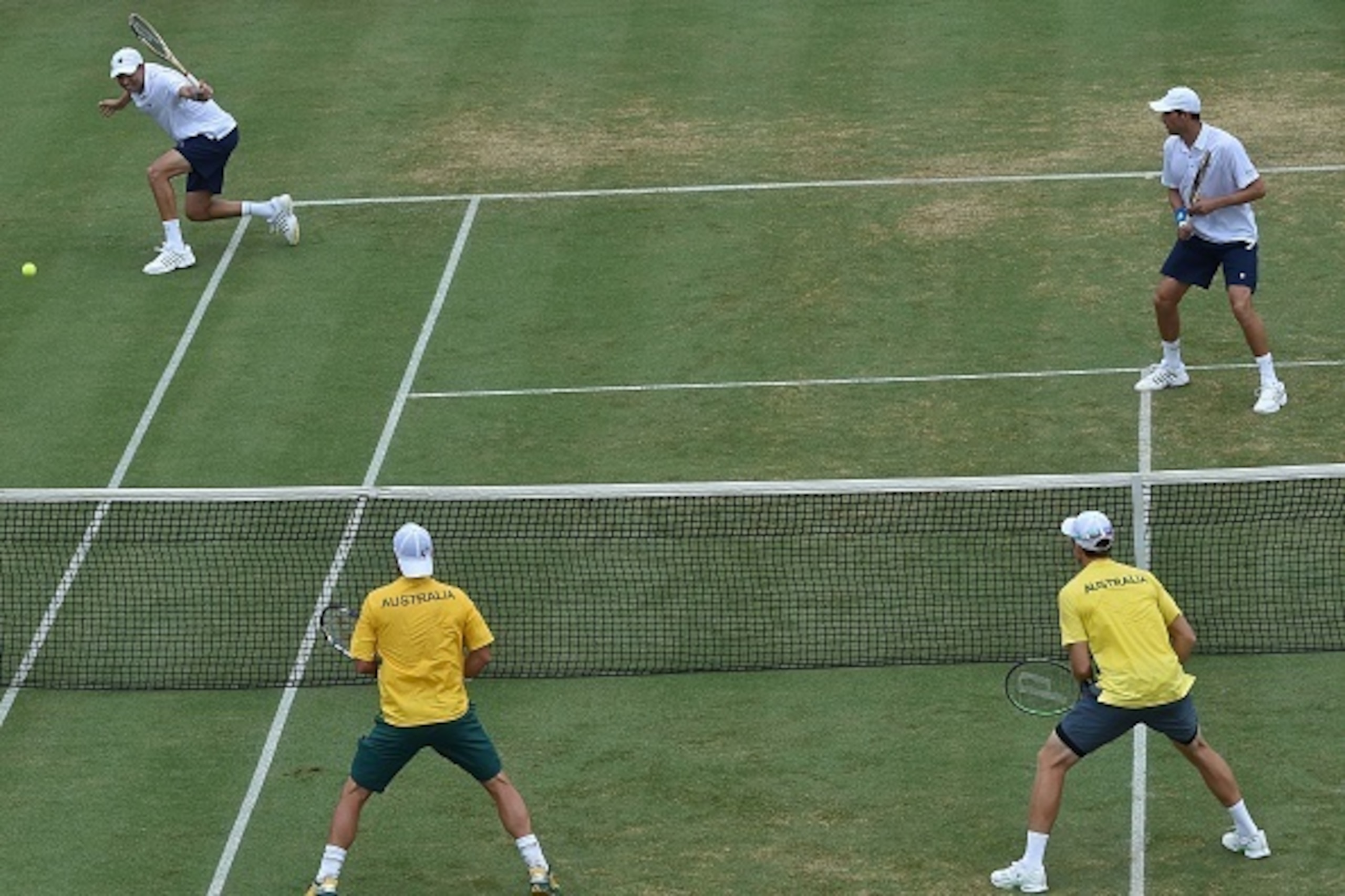 Mike Bryan (R) watches as brother Bob Bryan of the US (L) plays a shot down the line past Lleyton Hewitt (bottom L) and John Peers of Australia (bottom R) during the men's doubles match at the World Group first round Davis Cup tennis tournament at Kooyong