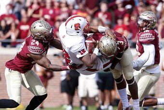 TALLAHASSEE, FL - NOVEMBER 14: Quarterback Jacoby Brissett #12 of the North Carolina State Wolfpack is sacked by Linebacker Terrance Smith #24 and Cornerback Derwin James #3 during the game against the Florida State Seminoles at Doak Campbell Stadium on B