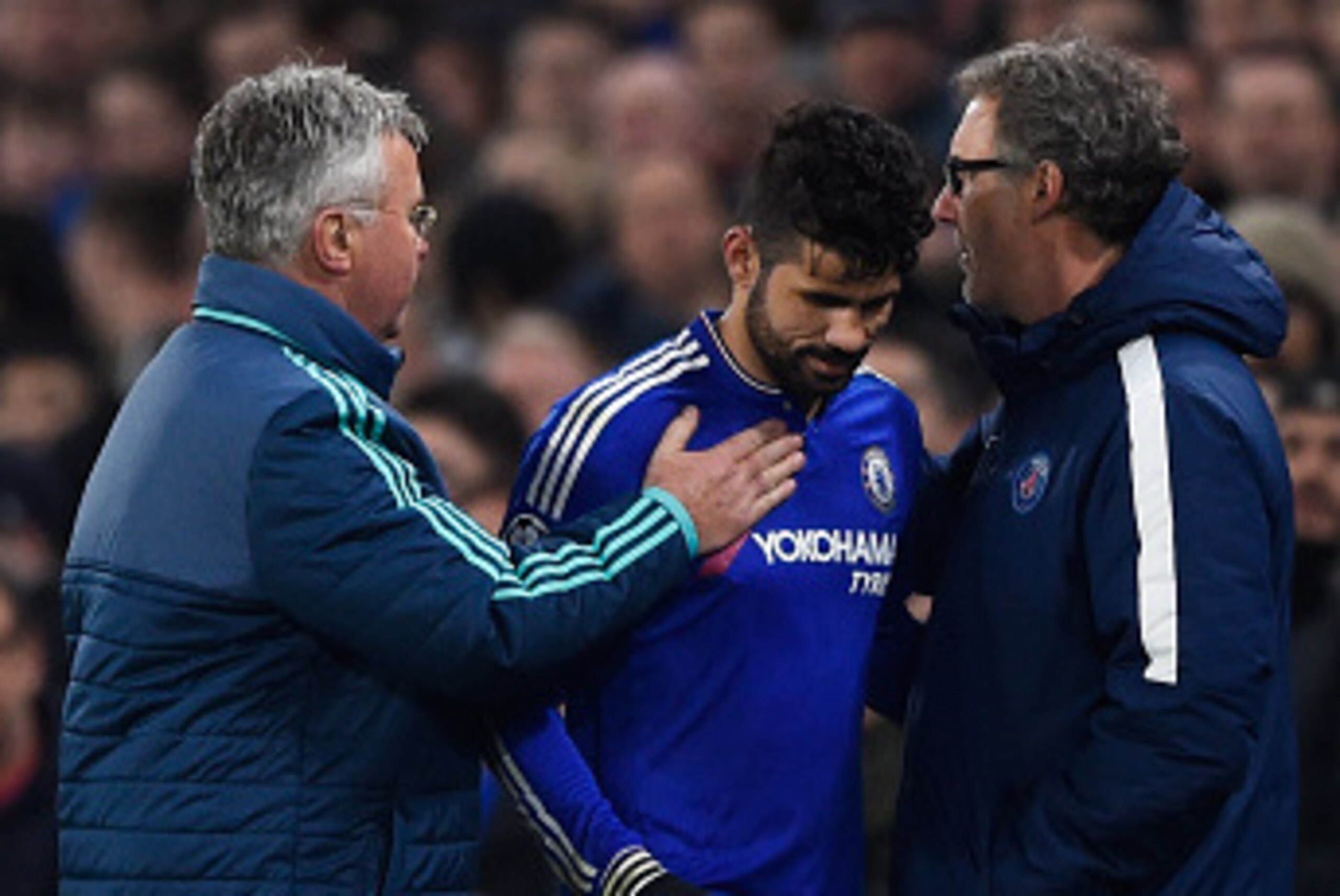 LONDON, ENGLAND - MARCH 09:  The injured Diego Costa of Chelsea is consoled by Head Coach Laurent Blanc (L) of PSG and Guus Hiddink (R) interim manager of Chelsea as he leaves the pitch during the UEFA Champions League round of 16, second leg match betwee