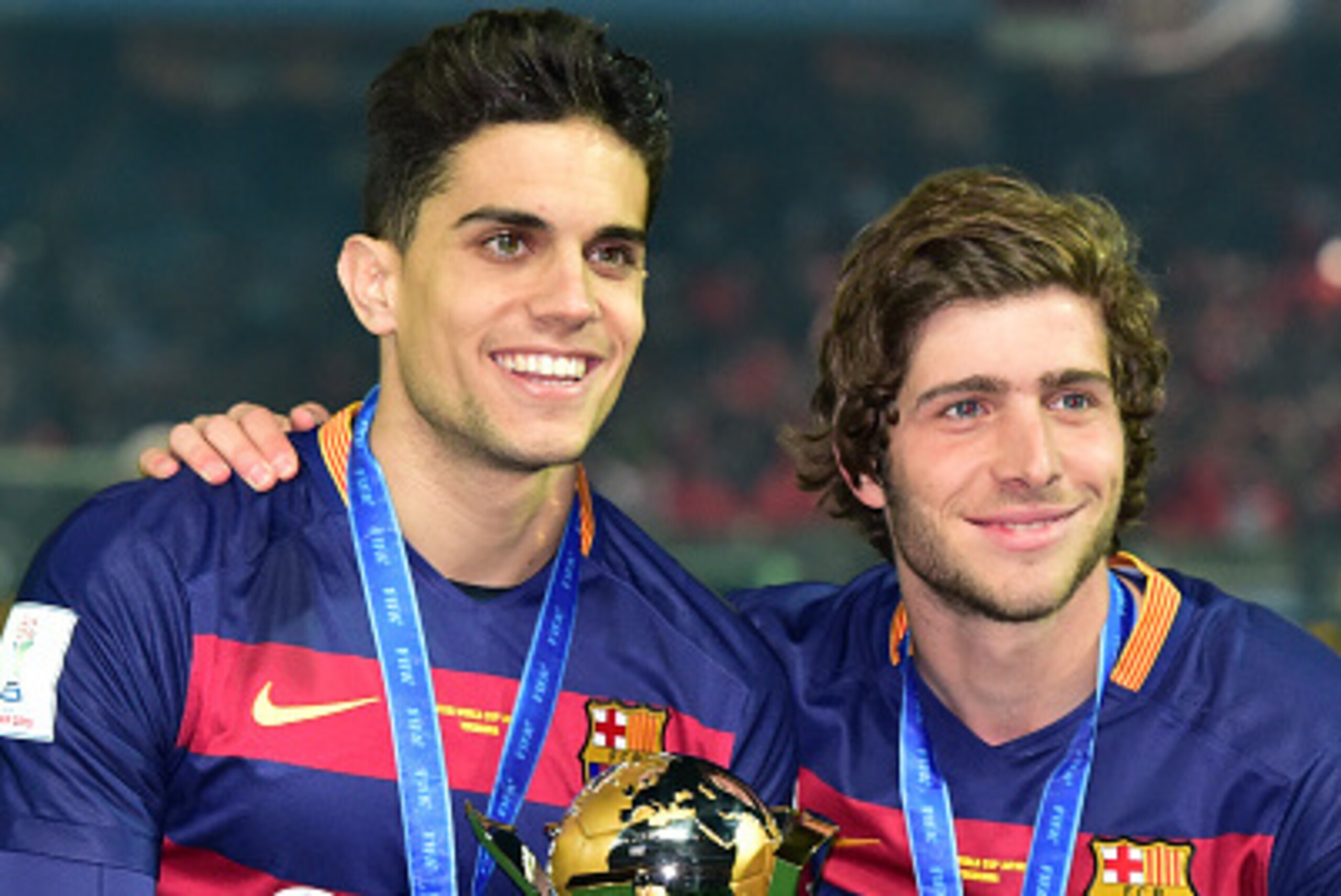 FC Barcelona player Marc Bartra (L) and Sergi Roberto (R) hold the trophy of the FIFA Club World Cup as Barcelona won the FIFA Club World Cup in the final in Yokohama, suburban Tokyo on December 20, 2015. FC Barcelona defeated River Plate 3-0.   AFP PHOTO