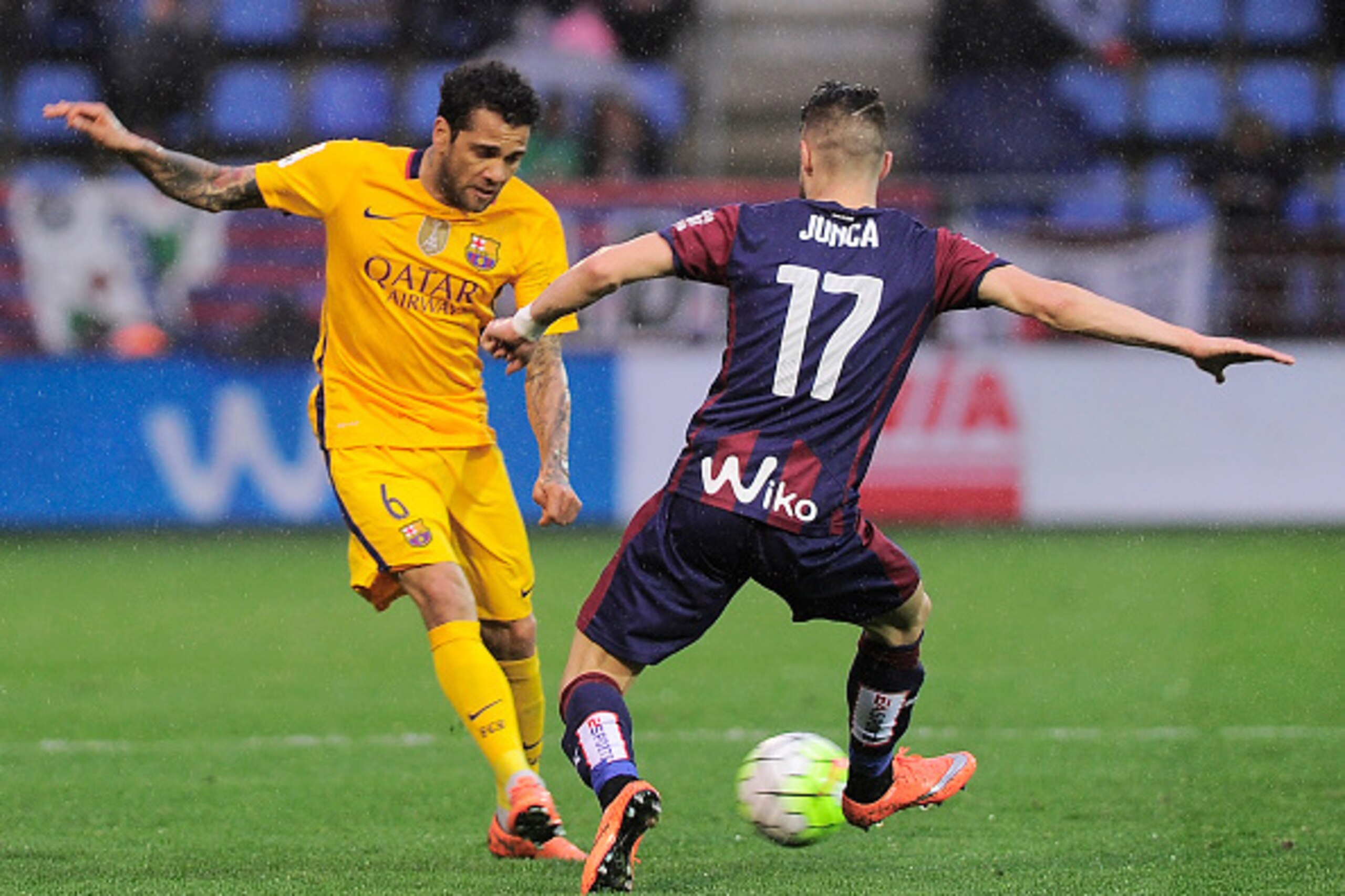 Barcelona's Brazilian defender Dani Alves (L) vies with Eibar's forward David Junca (R) during the Spanish league football match SD Eibar vs FC Barcelona at the Ipurua stadium in Eibar on March 6, 2016. / AFP / ANDER GILLENEA        (Photo credit should r