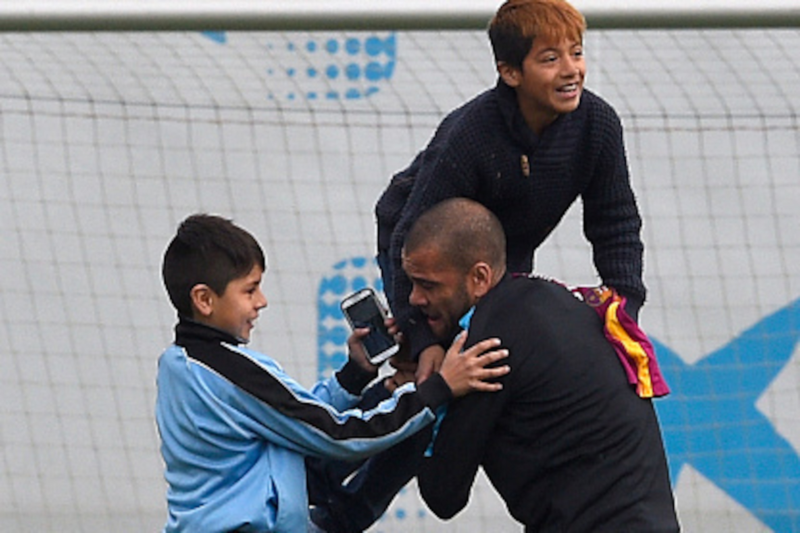 Barcelona's Brazilian defender Dani Alves plays with children who gate-crashed the training session at the Sports Center FC Barcelona Joan Gamper in Sant Joan Despi, near Barcelona on March 14, 2016, on the eve of the UEFA Champions League last sixteen se