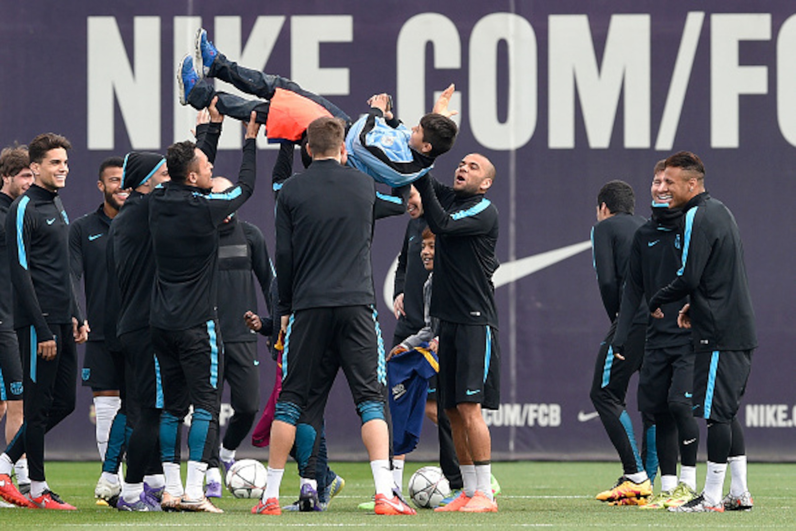 Barcelona's players throw a child in the air after a group of  gate-crashed the training session at the Sports Center FC Barcelona Joan Gamper in Sant Joan Despi, near Barcelona on March 14, 2016, on the eve of the UEFA Champions League last sixteen secon