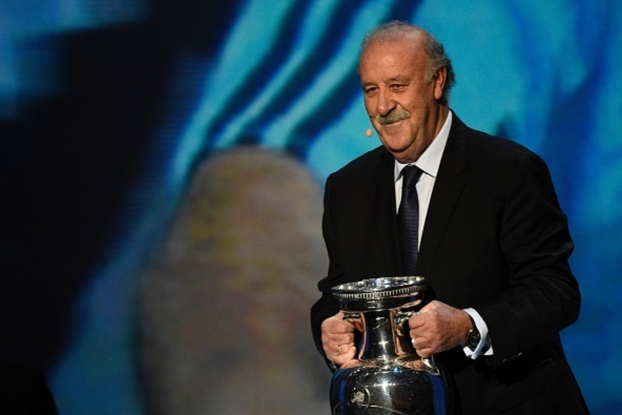 Spain's coach Vicente del Bosque arrives on stage with the trophy before the final draw of the UEFA Euro 2016 football tournament in Paris on December 12, 2015.  AFP PHOTO / FRANCK FIFE / AFP / FRANCK FIFE        (Photo credit should read FRANCK FIFE/AFP/
