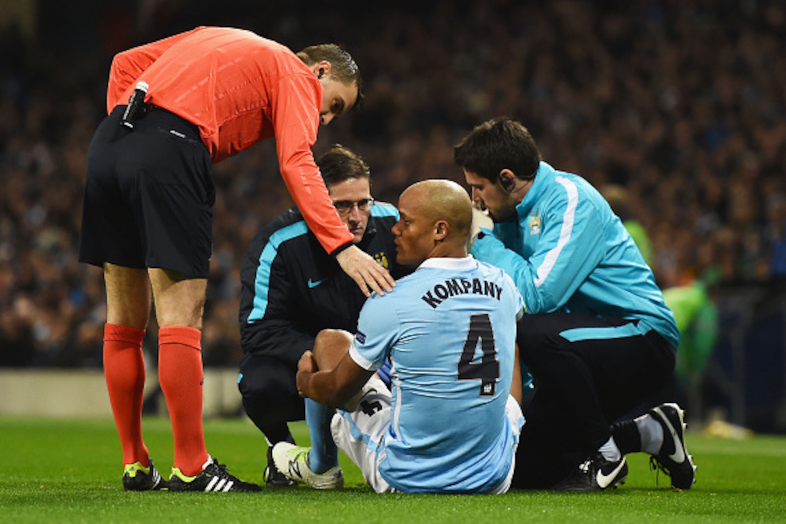 MANCHESTER, ENGLAND - MARCH 15:  An injured Vincent Kompany of Manchester City (4) is given treatment during the UEFA Champions League round of 16 second leg match between Manchester City FC and FC Dynamo Kyiv at the Etihad Stadium on March 15, 2016 in Ma