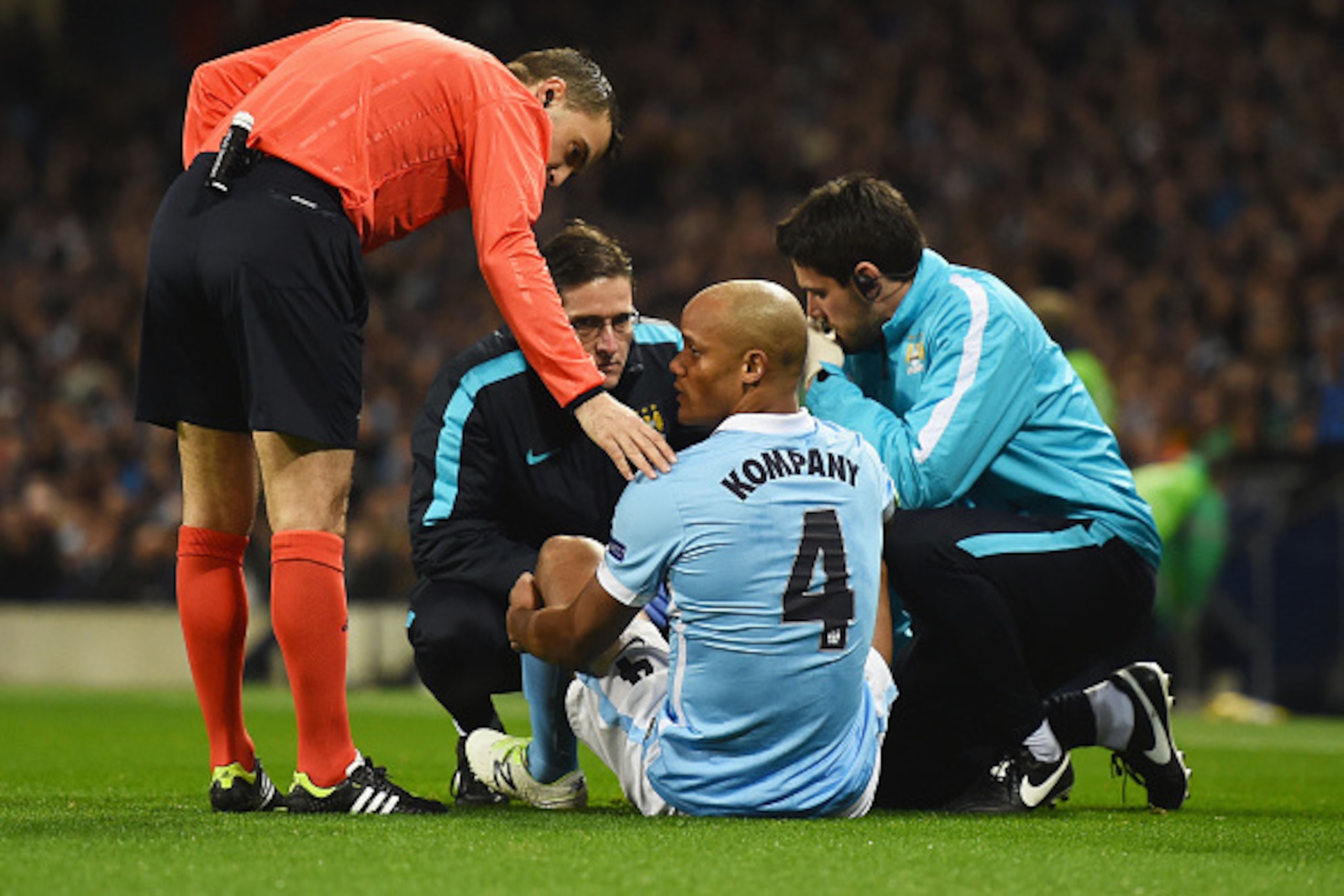 MANCHESTER, ENGLAND - MARCH 15:  An injured Vincent Kompany of Manchester City (4) is given treatment during the UEFA Champions League round of 16 second leg match between Manchester City FC and FC Dynamo Kyiv at the Etihad Stadium on March 15, 2016 in Ma
