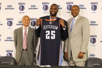 CHARLOTTE, NC - JULY 10:  Al Jefferson #25 of the Charlotte Bobcats poses with his uniform alongside General Manager Rich Cho and President of Basketball Operations Rod Higgins during his intro to the media at the Time Warner Cable Arena on July 10, 2013 