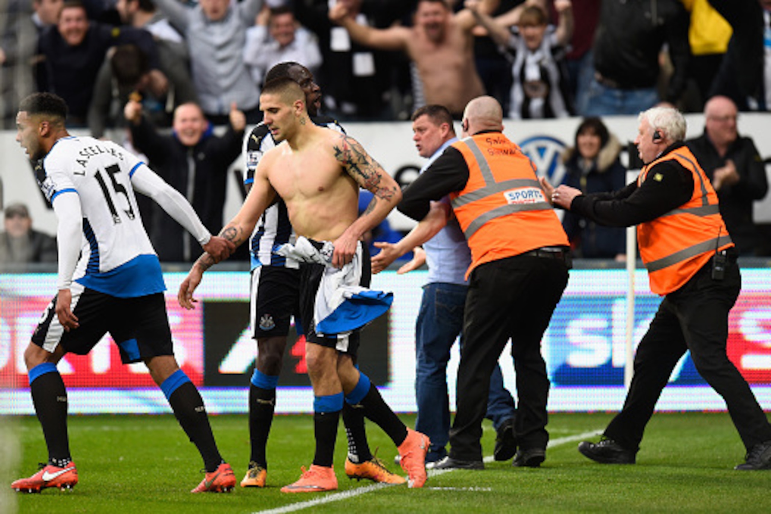 NEWCASTLE UPON TYNE, ENGLAND - MARCH 20: Aleksandar Mitrovic of Newcastle United celebrates with team mates as the fan who had joined him in celebrating the equalising goal is carted off during the Barclays Premier League match between Newcastle United a NEWCASTLE UPON TYNE, ENGLAND - MARCH 20: Aleksandar Mitrovic of Newcastle United celebrates with team mates as the fan who had joined him in celebrating the equalising goal is carted off during the Barclays Premier League match between Newcastle United a